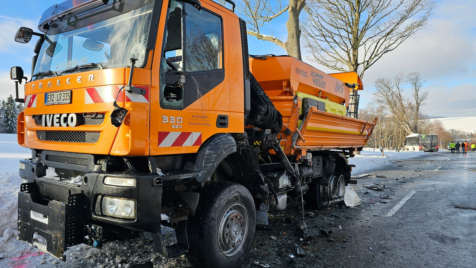Nach der Kollision mit dem Schulbus steht ein demoliertes Streufahrzeug am Straßenrand.