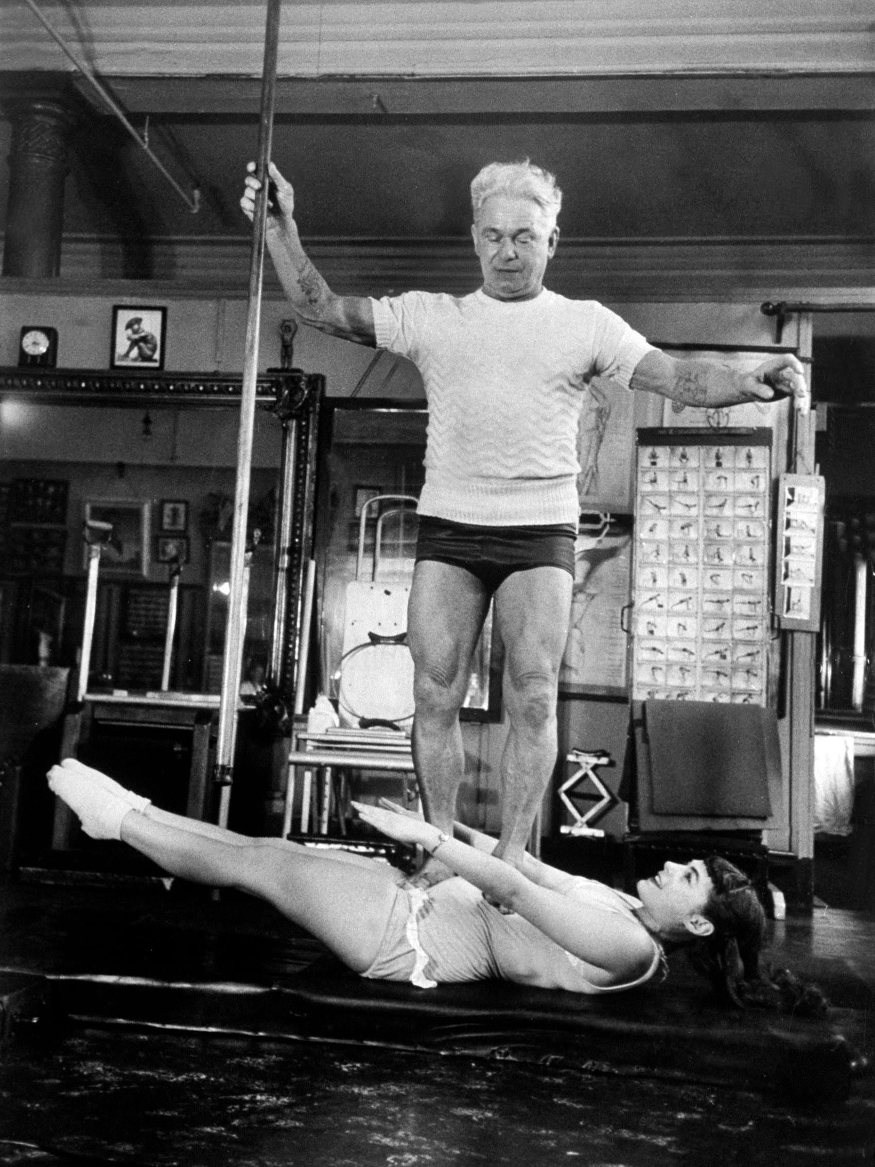 February 1951: Opera singer Roberta Peters balancing her trainer, Joseph Pilates, on her operatic breadbasket.