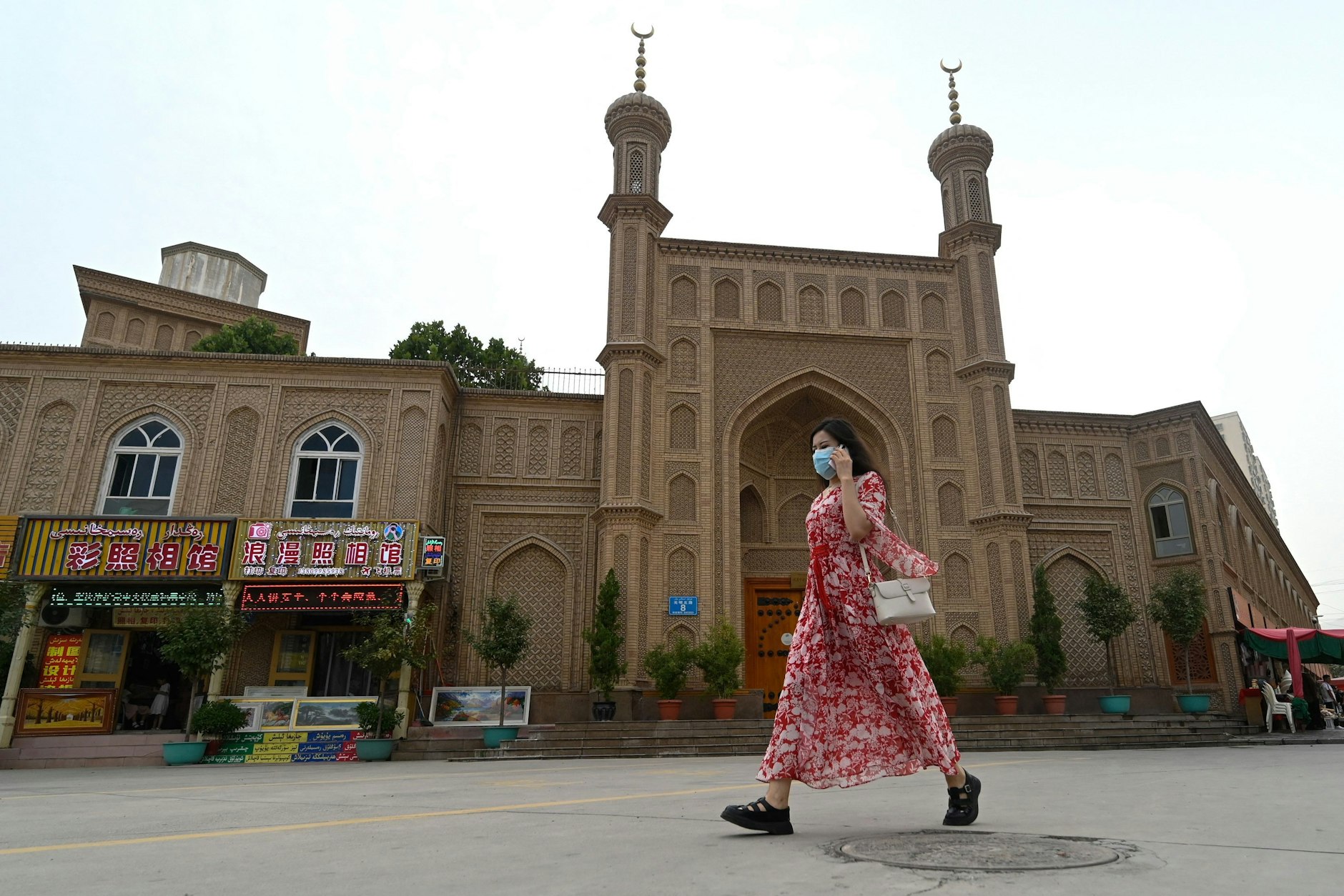 Eine Frau spaziert vor einer Moschee in der Stadt Artux in Xinjiang.