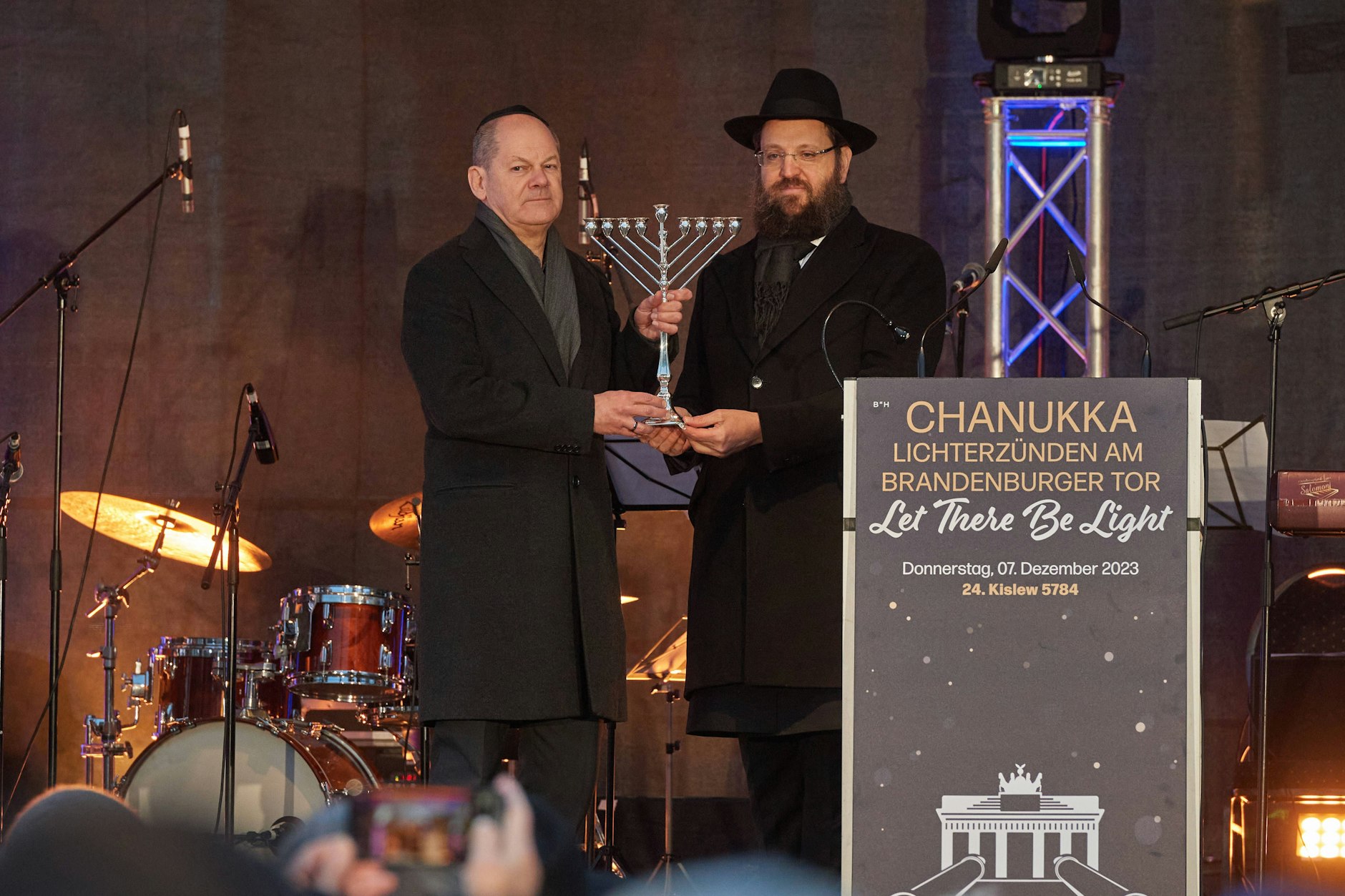 Vor dem Brandenburger Tor in Berlin wurde am Donnerstag das erste Licht an einem zehn Meter hohen Chanukka-Leuchter entzündet. Rabbi Teichtal überreicht dem Bundeskanzler zum Dank einen Chanukka-Leuchter.