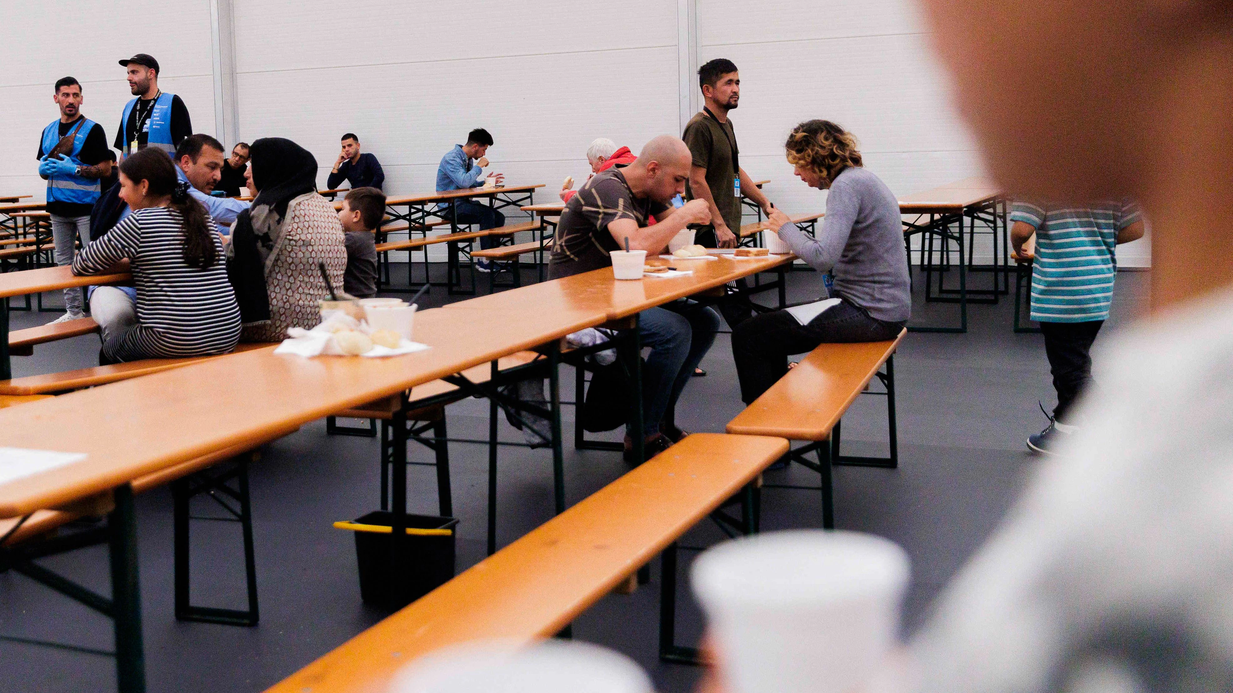 Geflüchtete sitzen beim Essen in einem Aufenthaltsraum vom Gelände des Ankunftszentrums Tegel.