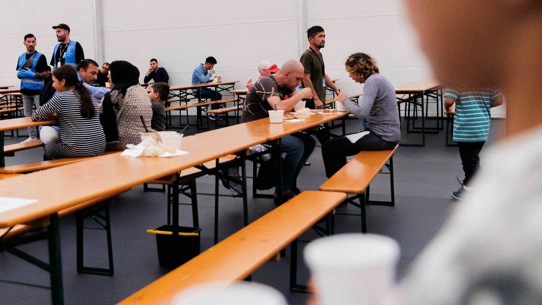 Geflüchtete sitzen beim Essen in einem Aufenthaltsraum vom Gelände des Ankunftszentrums Tegel.