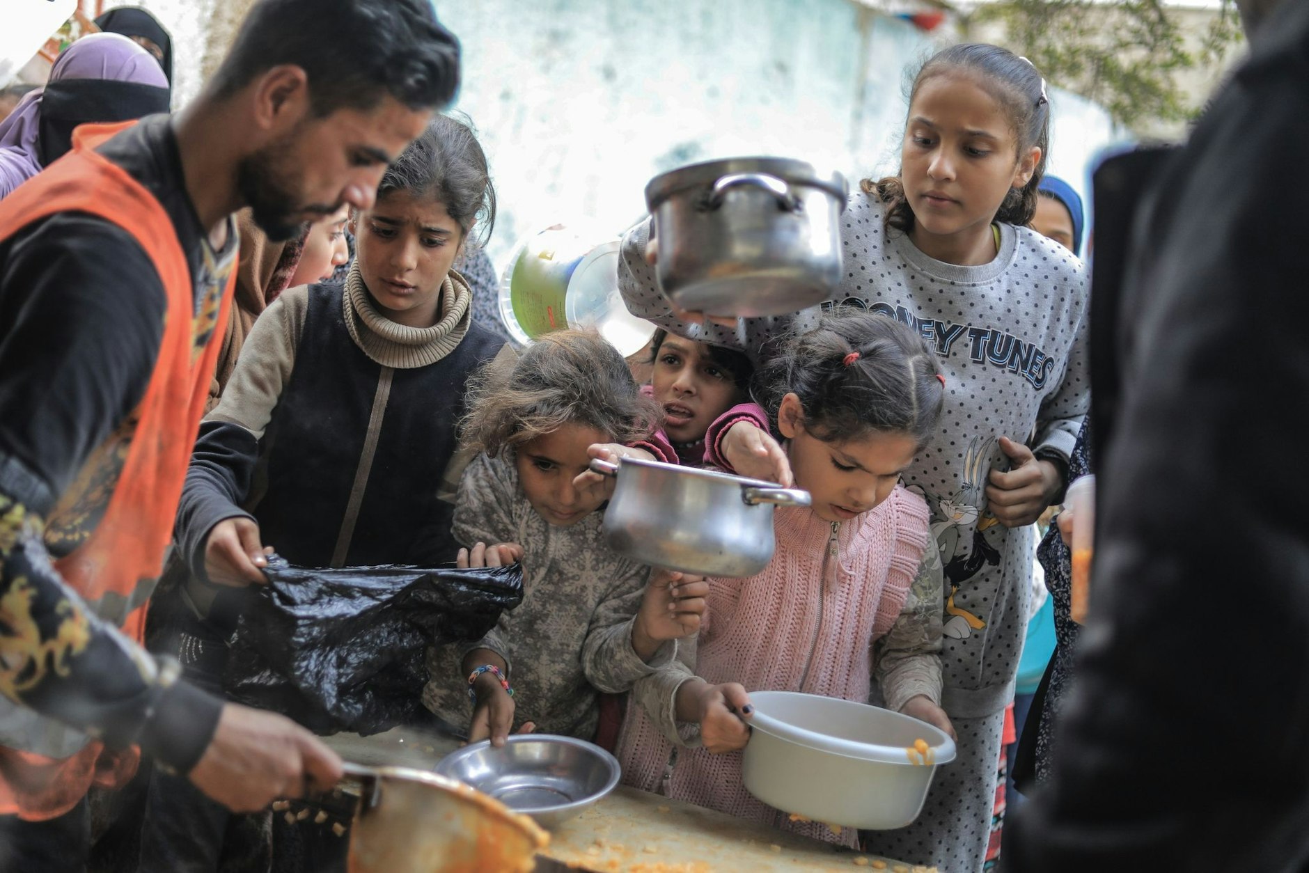 dpatopbilder - Die Not im Gazastreifen wird immer schlimmer. Menschen stehen in Rafah im Süden des abgeriegelten Küstengebiets mit Töpfen, Schalen und Tüten bei einer Essensausgabe an.  