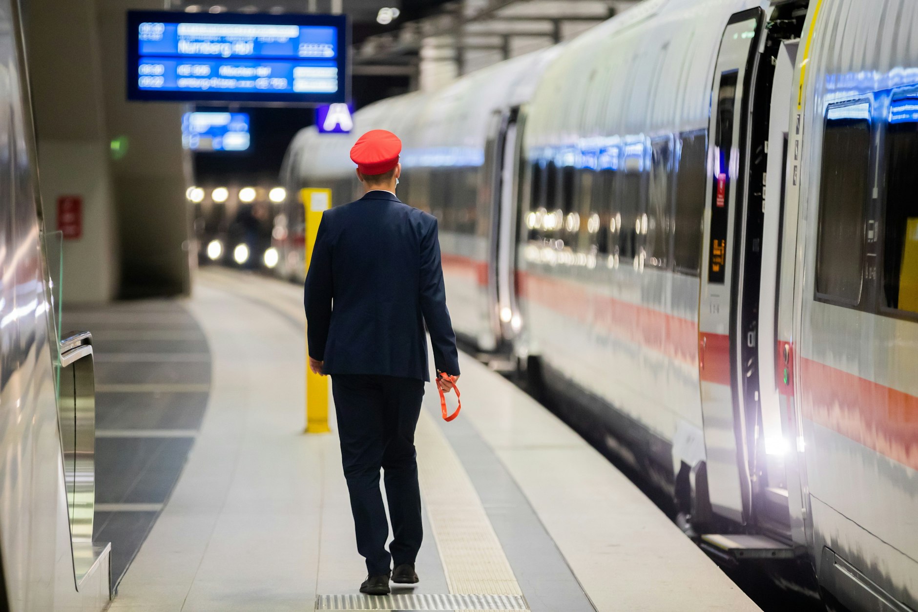 Ein Mitarbeiter der Bahnsteigaufsicht geht am Berliner Hauptbahnhof neben einem ICE.