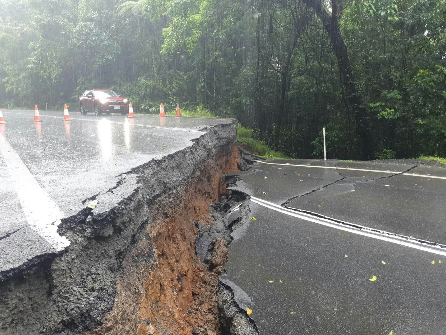 A supplied image obtained on Monday, December 18, 2023, shows a road split in half along the Palmerston Highway in far north Queensland following heavy rain and flooding from ex-tropical cyclone Jasper. (AAP Image/Supplied by Ergon Energy) NO ARCHIVING, EDITORIAL USE ONLY
