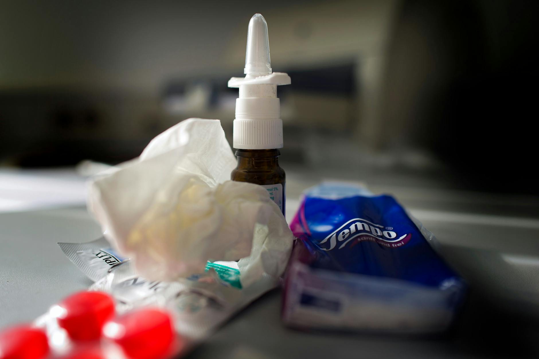 Anti-Erkältungsmittel wie Nasenspray, Halstabletten und Papiertaschentücher liegen auf einem Tisch. So dürfte es derzeit in vielen Haushalten aussehen.
