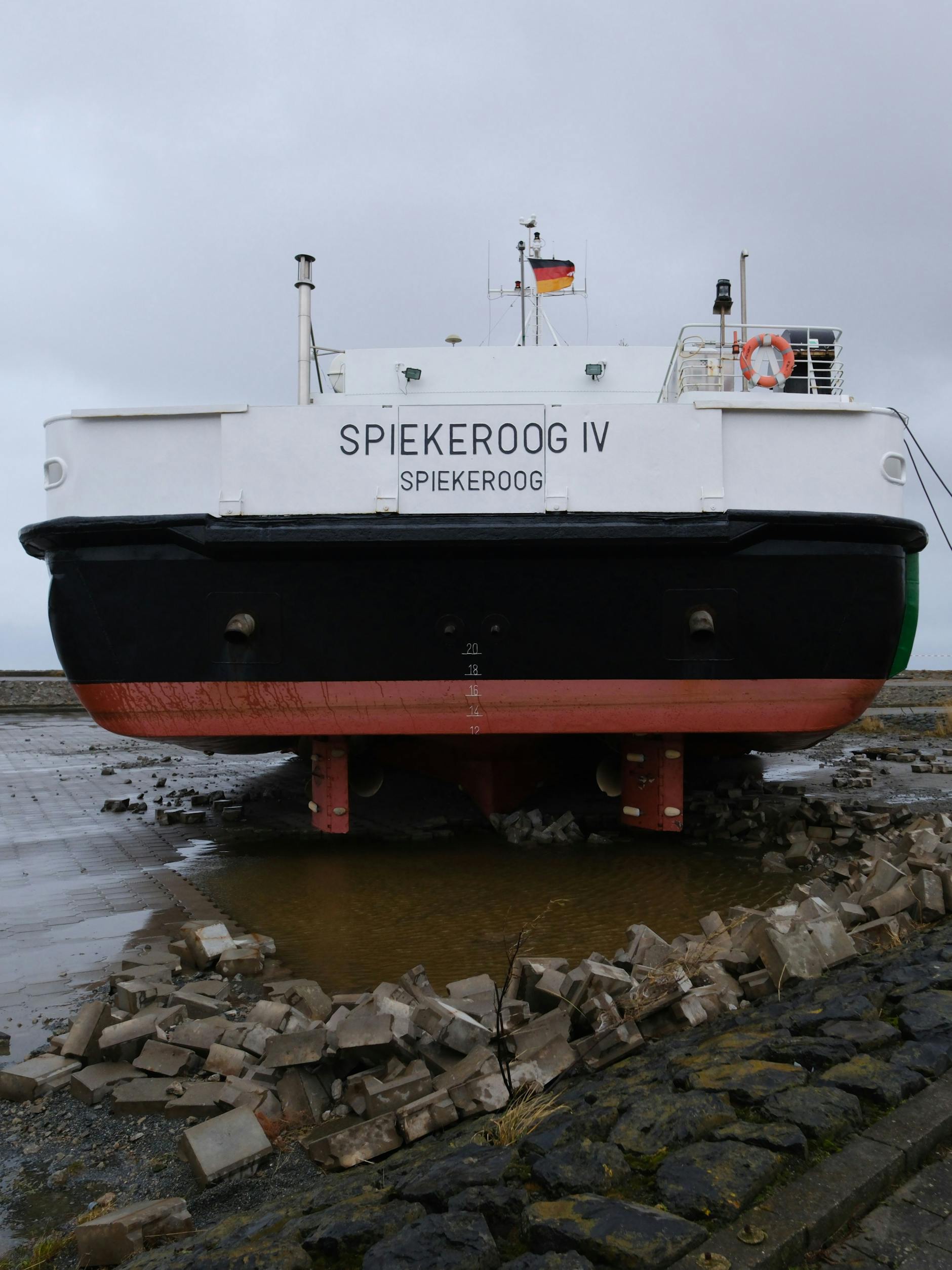 Die Fähre Spiekeroog IV ist am Freitagmorgen durch Sturm und Hochwasser über die Kaimauer geschoben worden und liegt auf einem Parkplatz am Fährterminal Neuharlingersiel.
