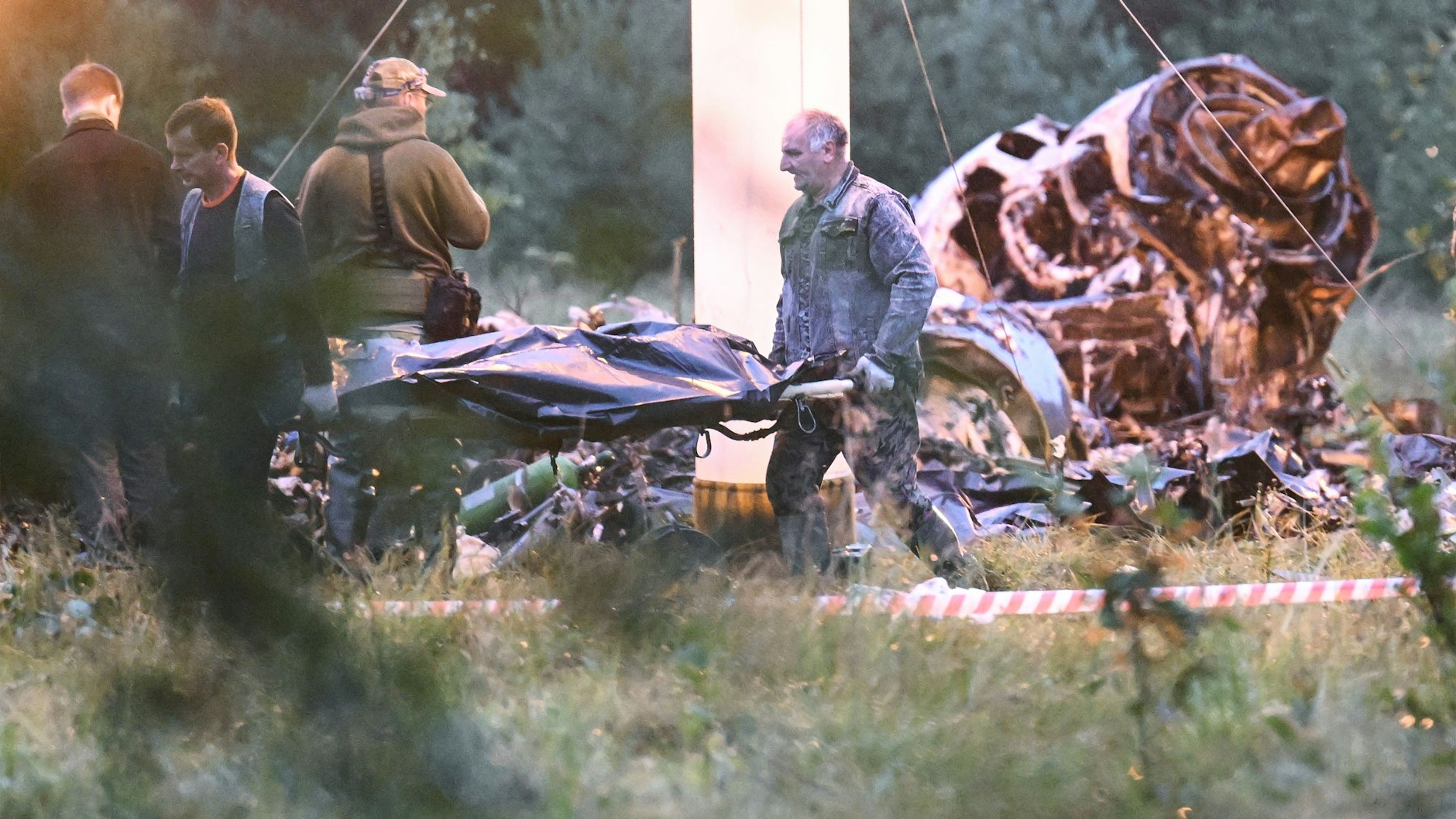 Eine Leiche wird vom Absturzort des Prigoschin-Jets weggetragen. Zehn Menschen starben bei dem mutmaßlichen Attentat.