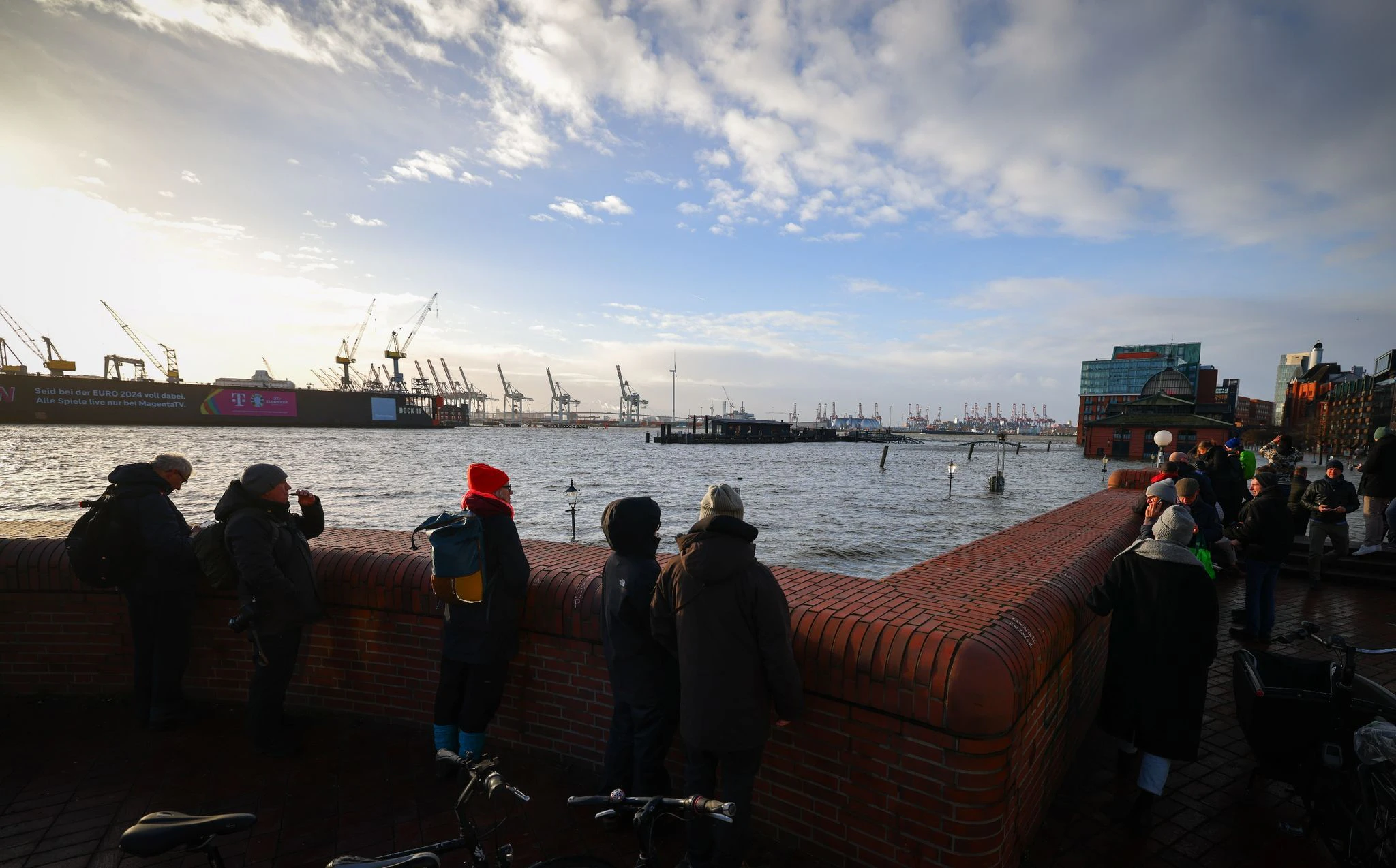 Schaulustige beobachten von einer Promenade am Hamburger Fischmarkt die Überflutung durch die Sturmflut.  