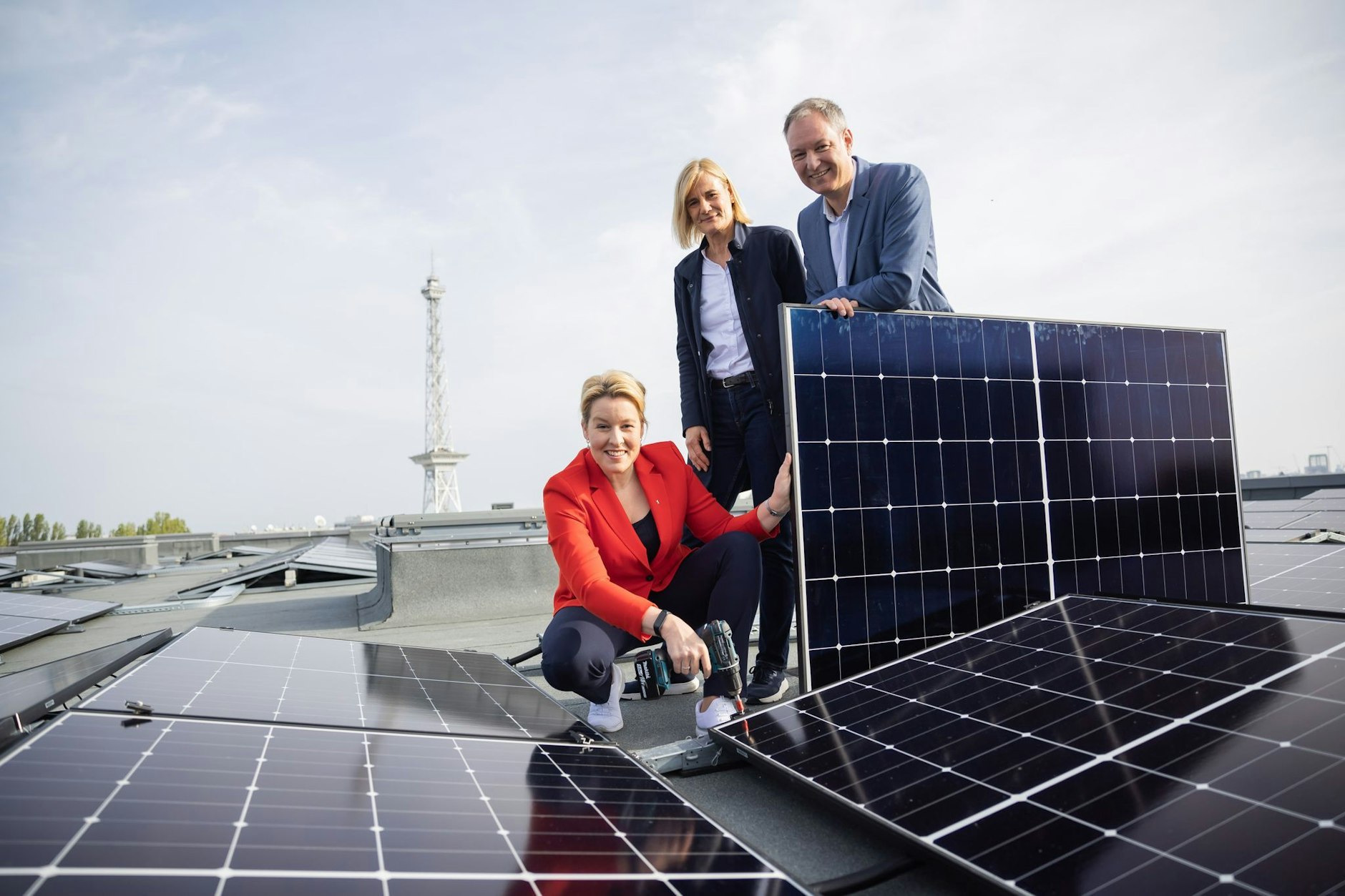 ARCHIV - Franziska Giffey (SPD, l-r), Kerstin Busch und Mario Tobias stehen auf einem Dach mit Solarplatten.  
