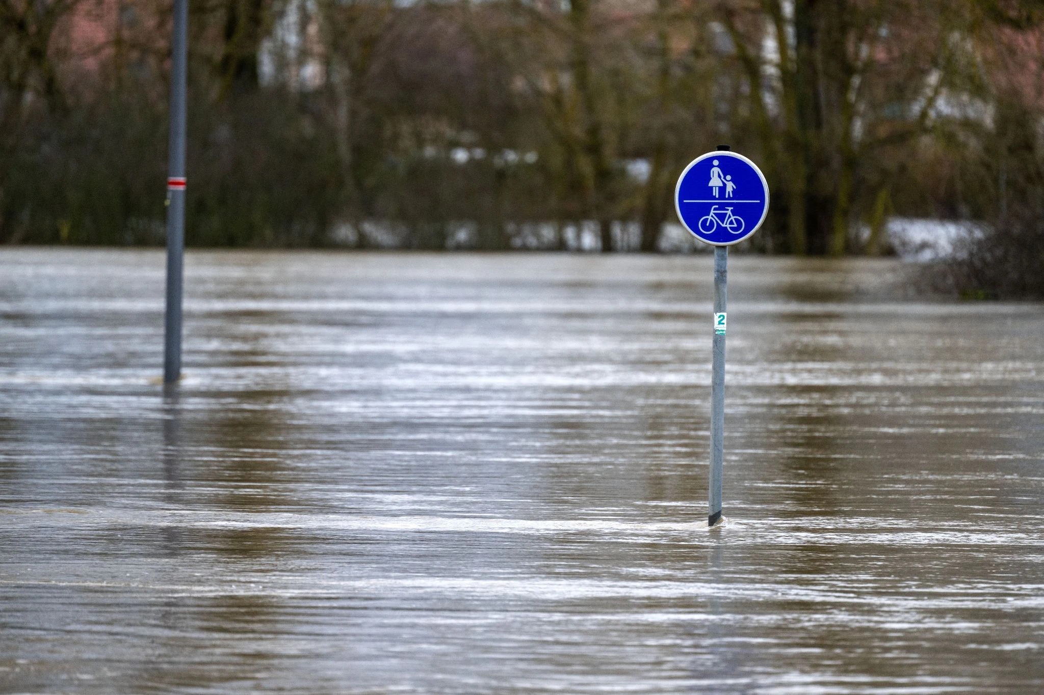 Ein Verkehrsschild für einen Geh- und Radweg bei Ebing in Bayern steht im Hochwasser. Die Hochwasserlage in Bayern hat sich etwas beruhigt.  