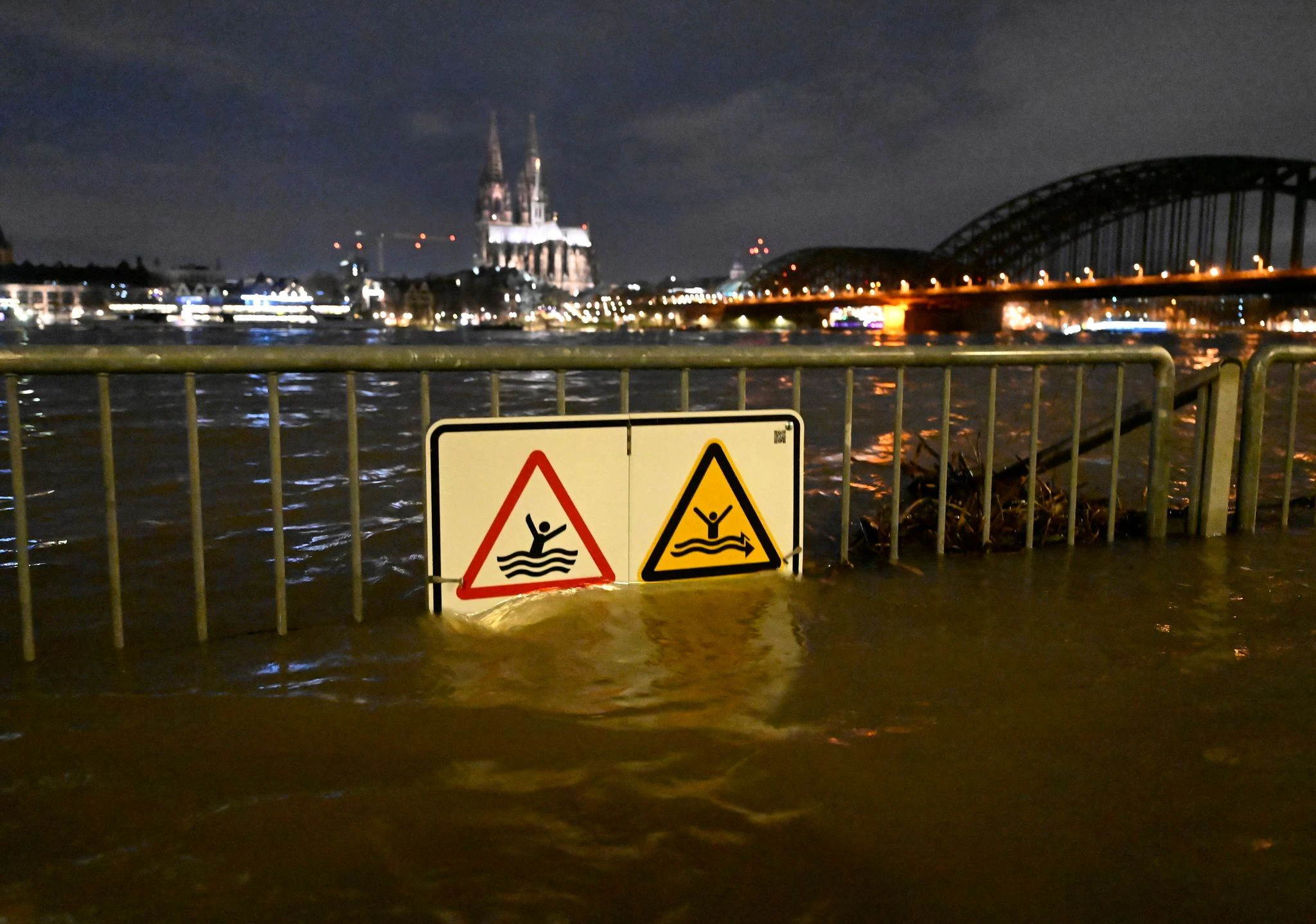 Warnschilder am Rheinufer in Köln sind vom Hochwasser umspült. Ergiebiger Dauerregen hat den Pegelstand des Rheins ansteigen lassen.  