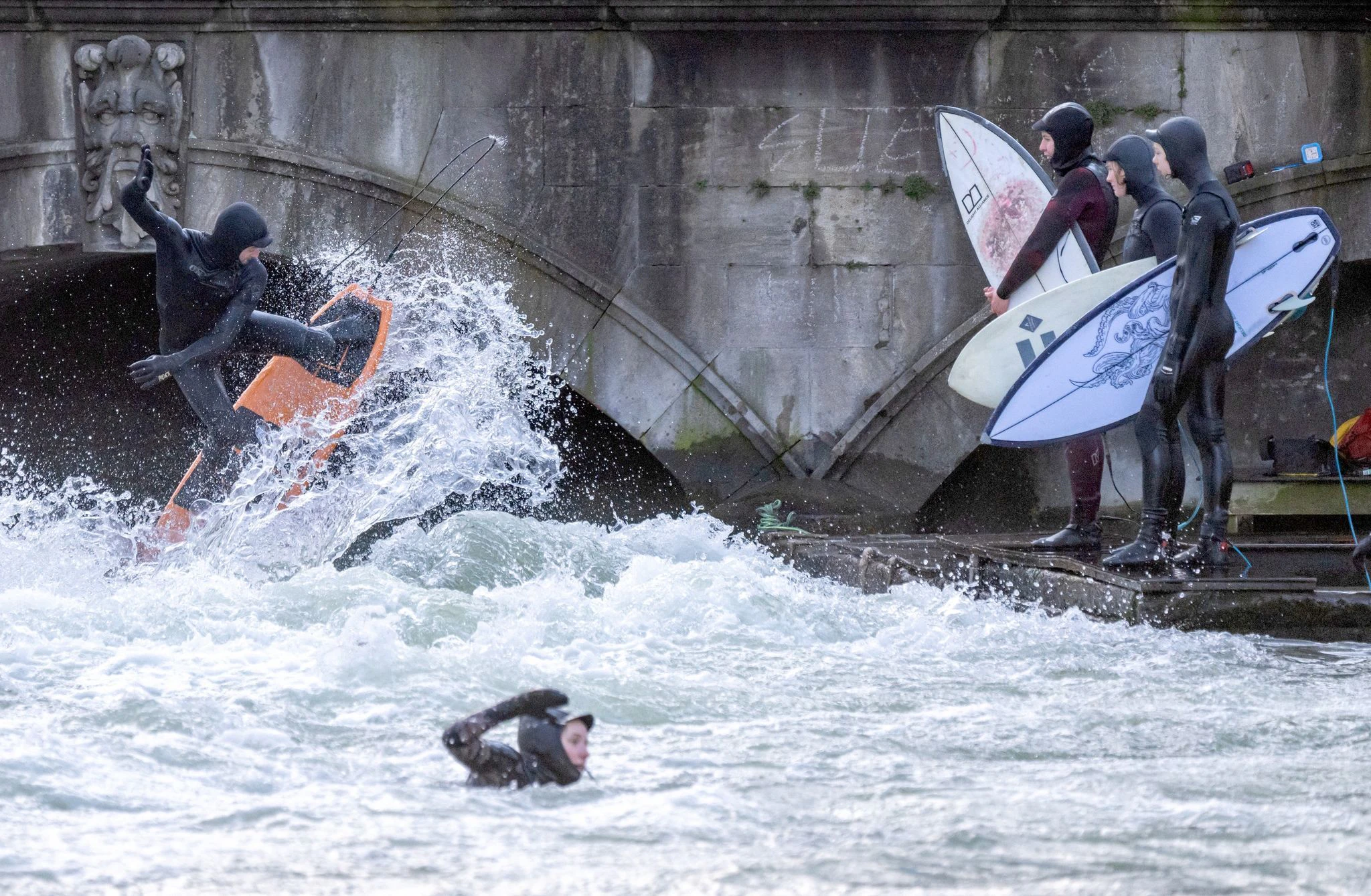 Brrr, das sieht kalt aus: Einige Mutige stürzen sich mit ihren Surfbrettern in den Eisbach in München.  