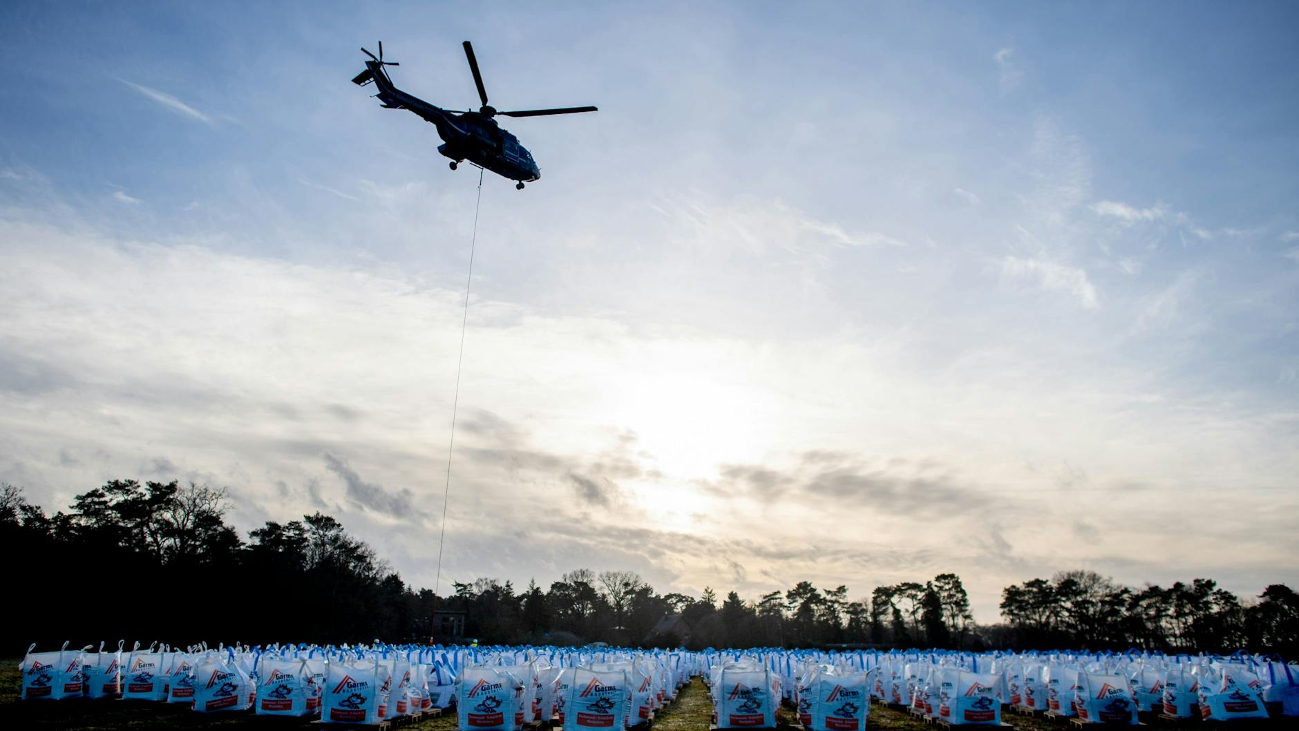Ein Hubschrauber vom Typ Super Puma der Bundespolizei ist am Barneführer Holz im Einsatz, um einen Deich mit großen Sandsäcken zu sichern.