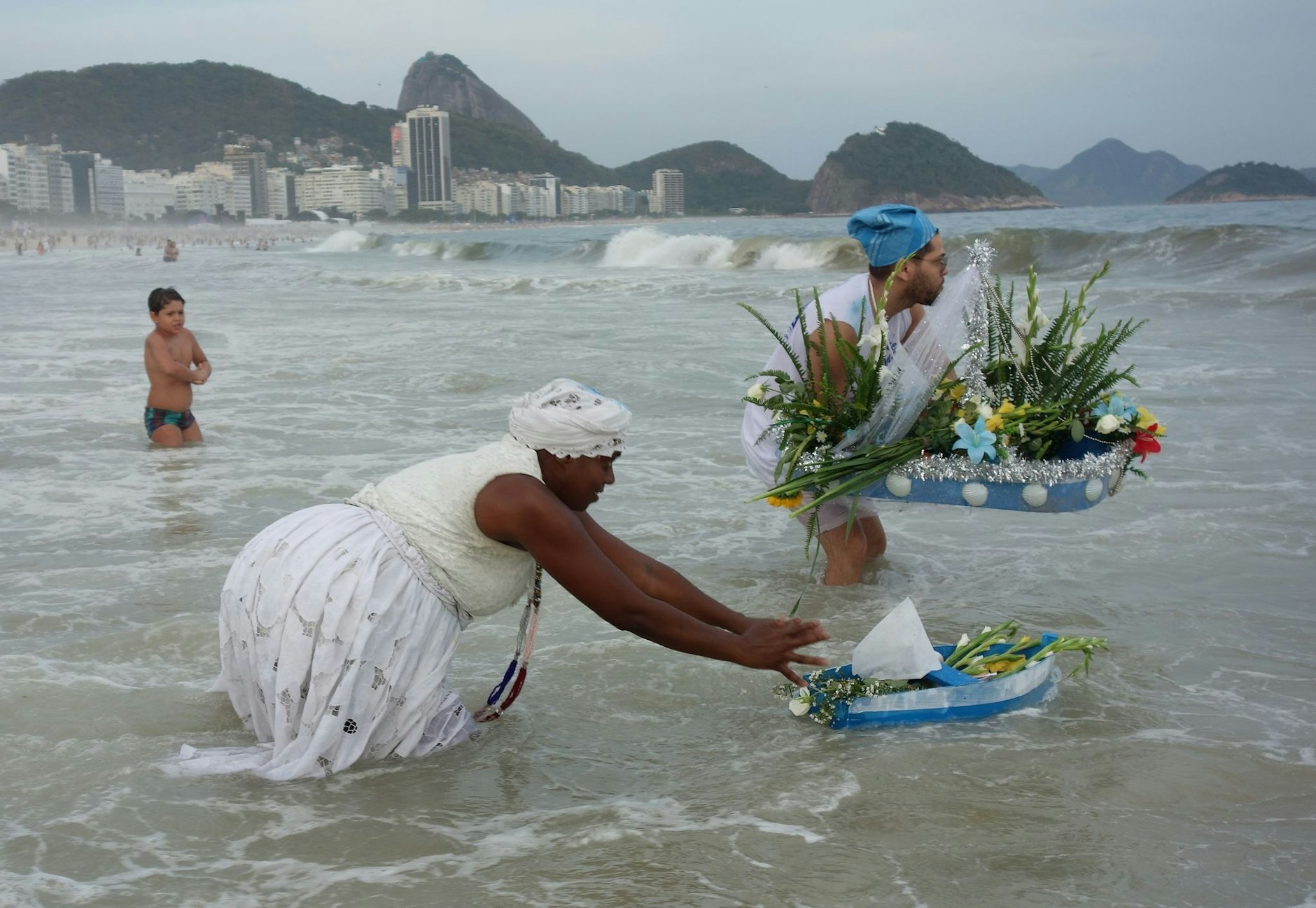 Menschen schicken in Rio De Janeiro handgefertigte Boote als Opfergabe aufs Meer hinaus. Hunderte von in Weiß gehüllten und mit Liliensträußen geschmückten Anhängern des afro-brasilianischen Umbanda-Glaubens versammeln sich am Strand der Copacabana, um die Meeresgöttin Lemanja mit einem traditionellen Neujahrsfest zu ehren.  