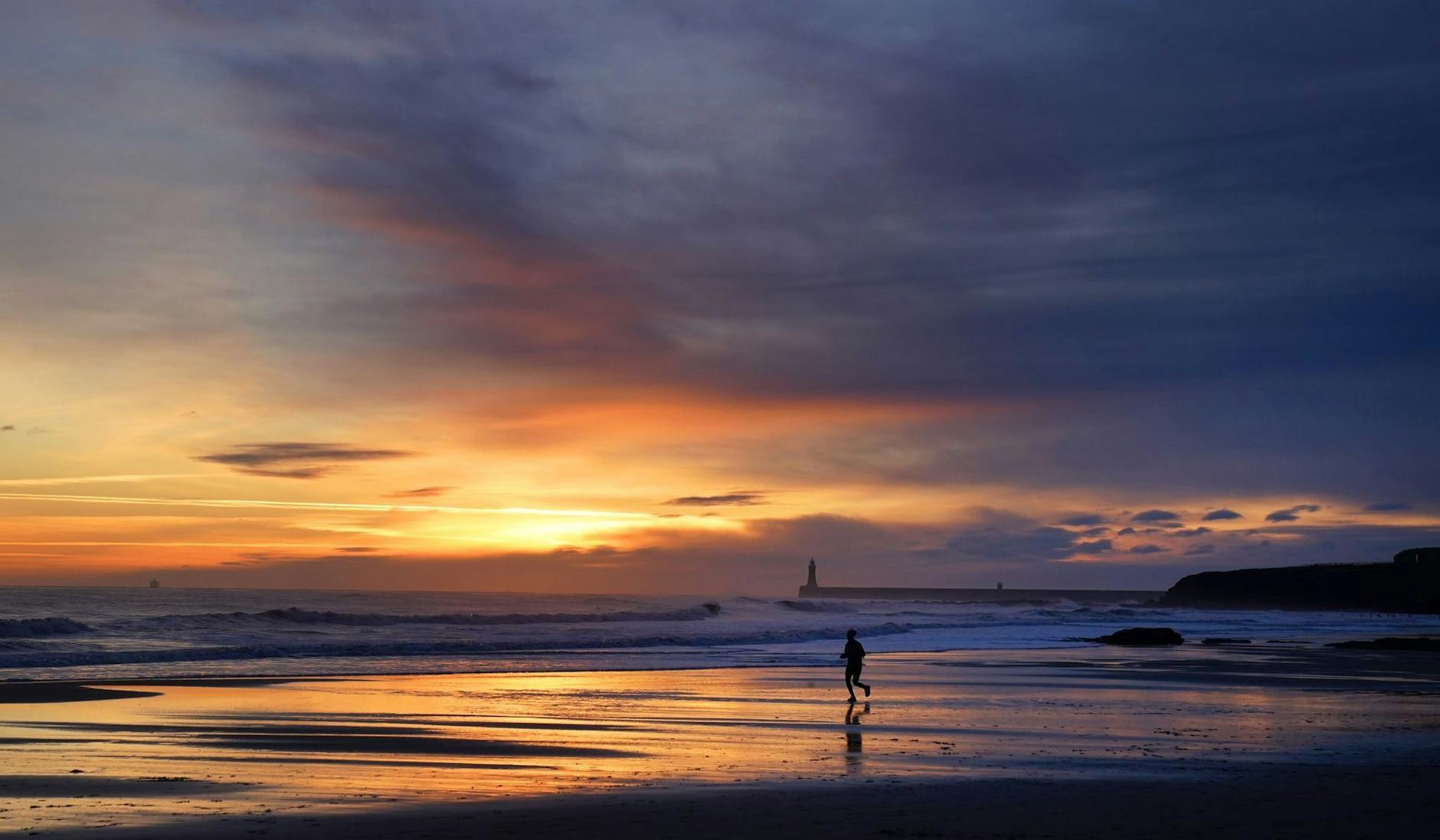 Die Ruhe vor dem Sturm: Ein Jogger läuft bei Sonnenaufgang am Strand von Tynemouth an der Nordostküste Englands. In Großbritannien kündigen sich zum Wochenende heftige Windböen an. Danach wird teils auch mit Schneefällen gerechnet.