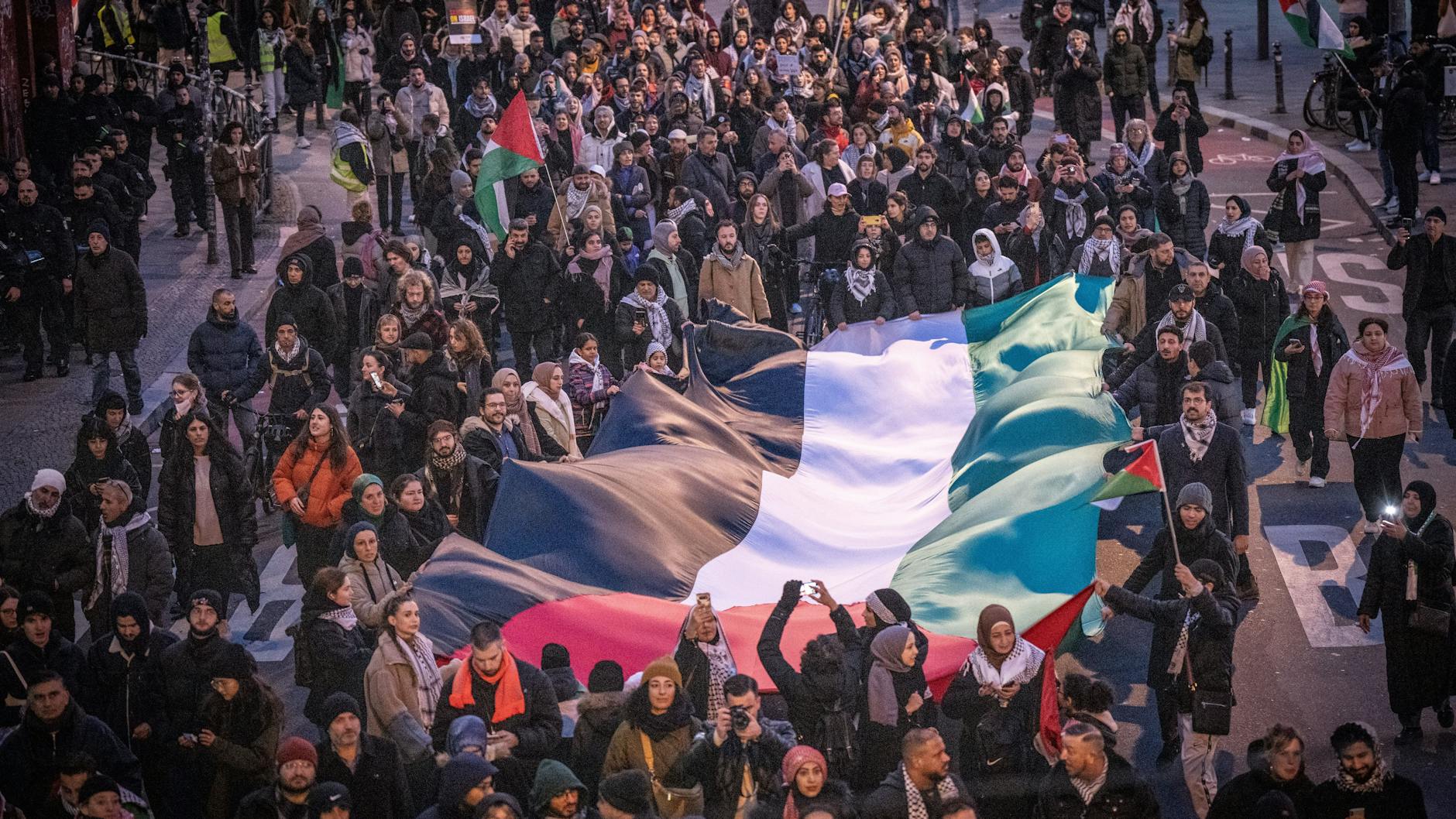 Teilnehmer tragen bei einer propalästinensischen Demonstration am Kottbusser Tor in Kreuzberg eine riesige palästinensische Flagge.