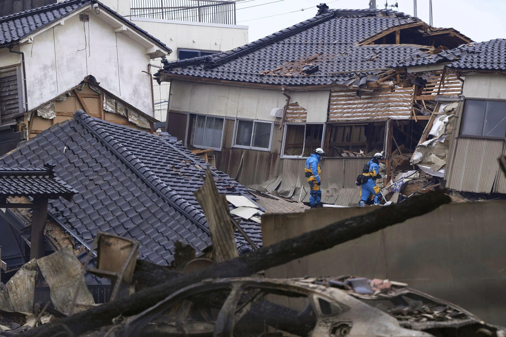 Einsatzkräfte der Polizei durchsuchen nach dem Erdbeben beschädigte Häuser in Wajima.  