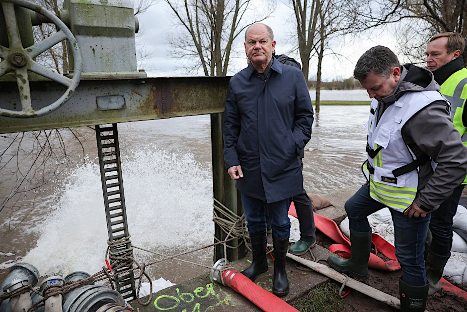 Bundeskanzler Olaf Scholz begutachtet ein Wehr in Sangerhausen.  