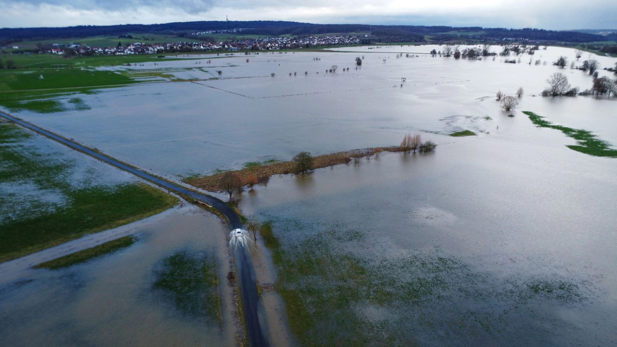 dpatopbilder - Ein Auto fährt am Rande des aufgestauten Rückhaltebeckens der Ohm. In Hessen ist noch keine Entspannung beim Hochwasser in Sicht.  
