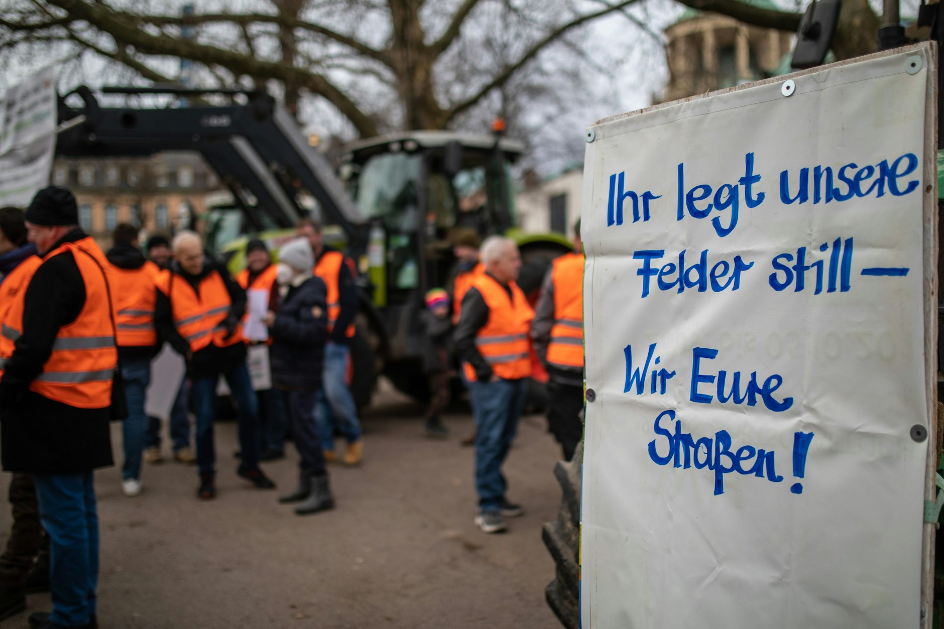 Bei einer Mahnwache vom Landesbauernverband Baden-Württemberg hängt ein Schild mit der Aufschrift „Ihr legt unsere Felder still – Wir eure Straßen“ an einem Traktor in Stuttgart.