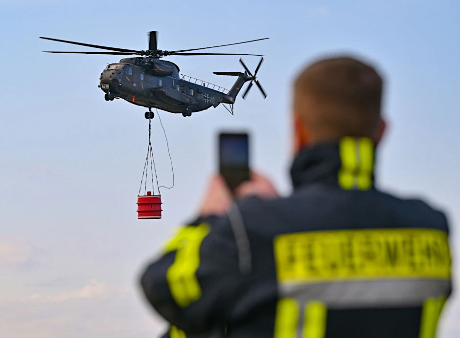 ARCHIV - Ein Hubschrauber vom Typ Sikorsky CH-53 der Luftwaffe fliegt mit einem Wasserbehälter während einer Übung über den Flugplatz Müncheberg-Eggersdorf.  