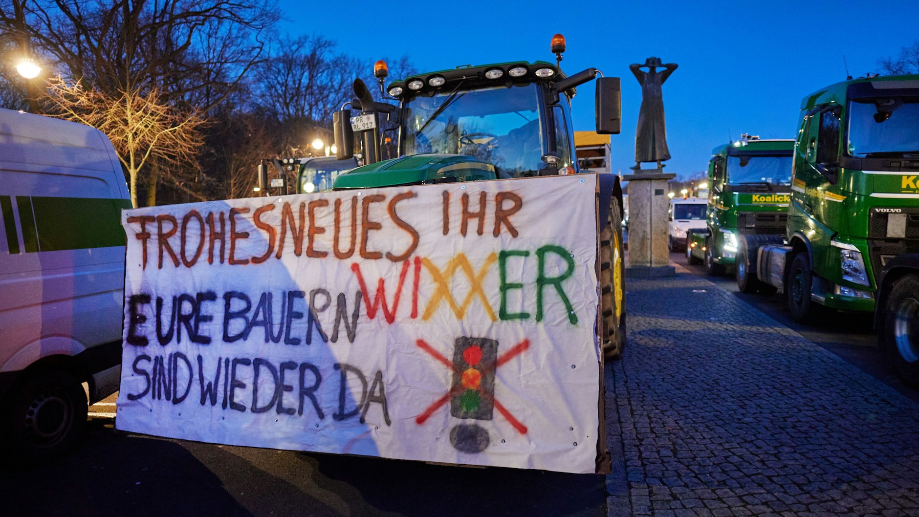 „Frohes Neues, ihr Wixxer, eure Bauern sind wieder da“ steht auf einem Schild, das an einem der Traktoren angebracht ist, die bei dem Bauernprotest auf der Straße des 17. Juni vor dem Brandenburger Tor stehen.