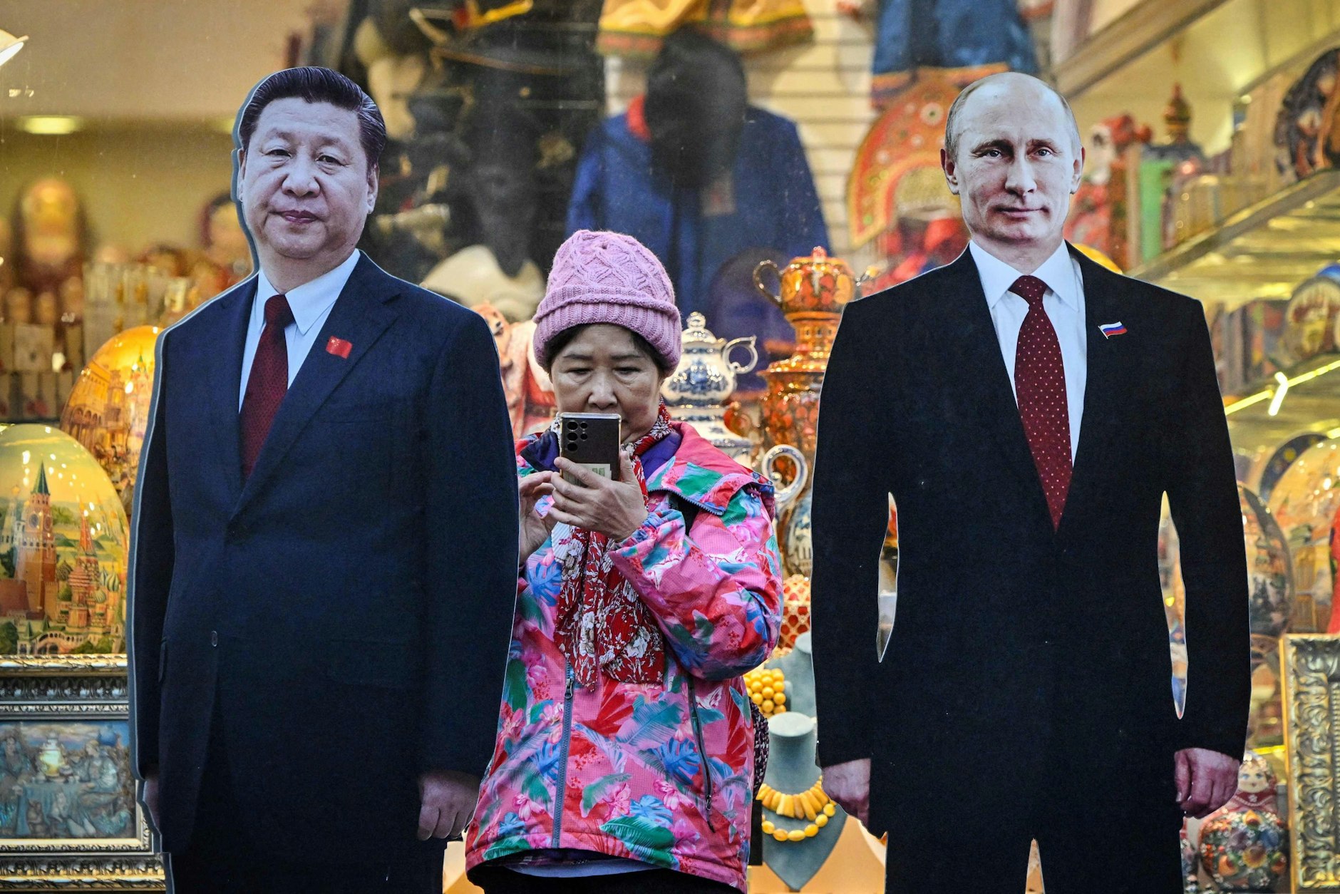 Eine Chinesin steht in der touristischen Arbat-Straße in der Innenstadt von Moskau neben Pappbildern, die den chinesischen Präsidenten Xi Jinping (l.) und seinen russischen Amtskollegen Wladimir Putin zeigen.