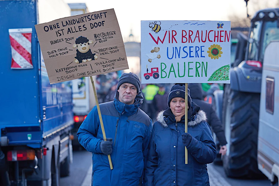 Transparente mit der Aufschrift "Ohne Landwirtschaft ist alles doof" und "Wir brauchen unsere Bauern" sind bei einem Bauernprotest auf der Straße des 17. Juni vor dem Brandenburger Tor zu sehen.  