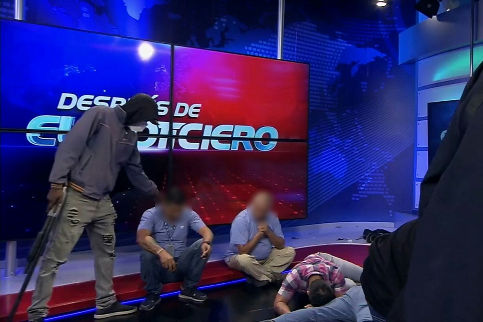 Dieser Screenshot eines Live-Videos des Fernsehsenders TC Television zeigt eine maskierte, bewaffnete Person, die sich während einer Live-Sendung über Journalisten stellt.
