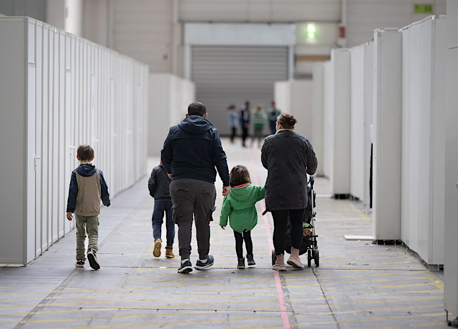 Eine Flüchtlingsfamilie geht durch die zu einer Massenunterkunft umfunktionierten Messehalle in Frankfurt.