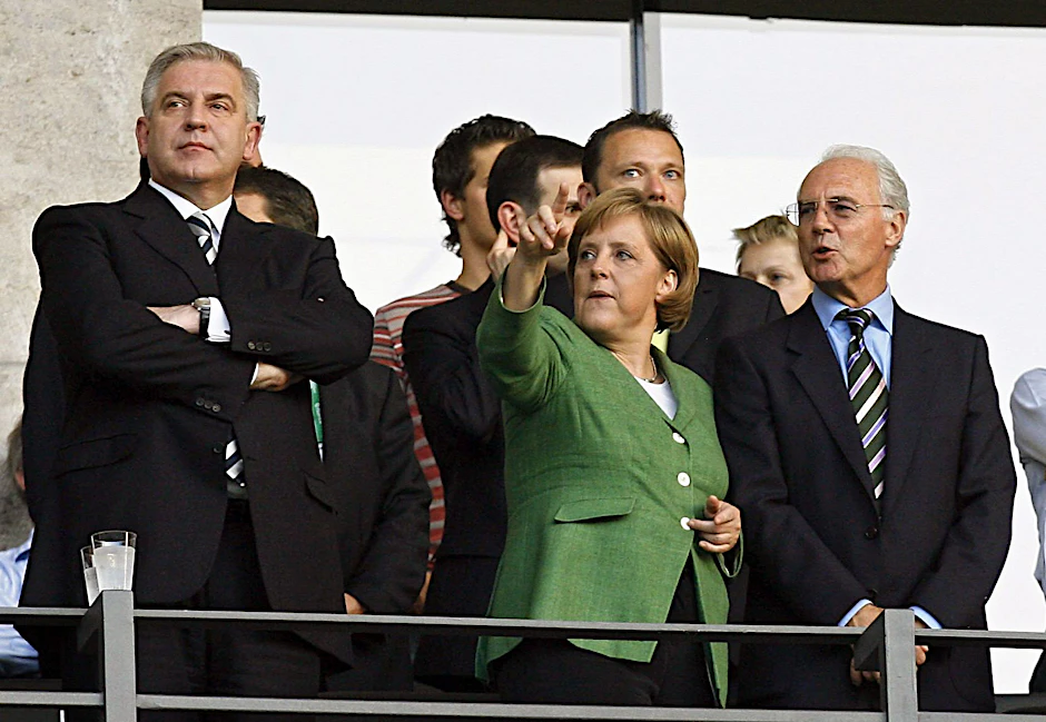 ARCHIV - Die damalige Kanzlerin Angela Merkel (M) und Franz Beckenbauer (r) bei einem Spiel der WM 2006 in Deutschland.  