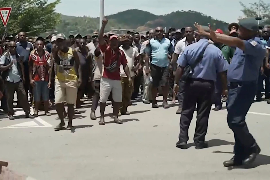 dpatopbilder - SCREENSHOT - Das Videostandbild zeigt zwei Polizisten neben einer aufgebrachten Menschenmenge in Port Moresby.  ng Corp/AP/dpa