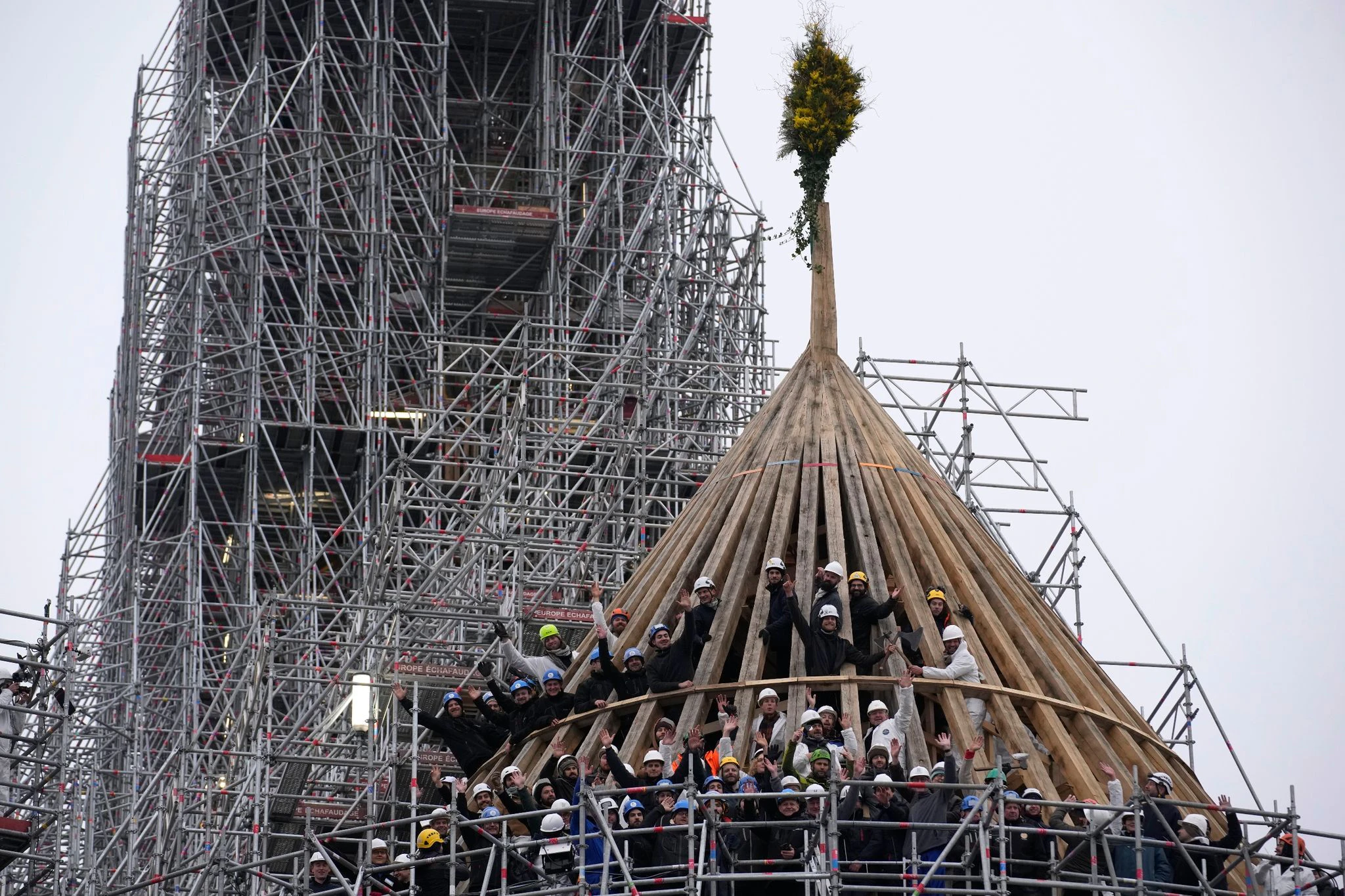 Mit einem Blumengesteck feiern die Arbeiter den Abschluss des Wiederaufbaus des Dachstuhls. Die Kathedrale Notre Dame in Paris war 2019 durch einen Brand schwer beschädigt worden.  