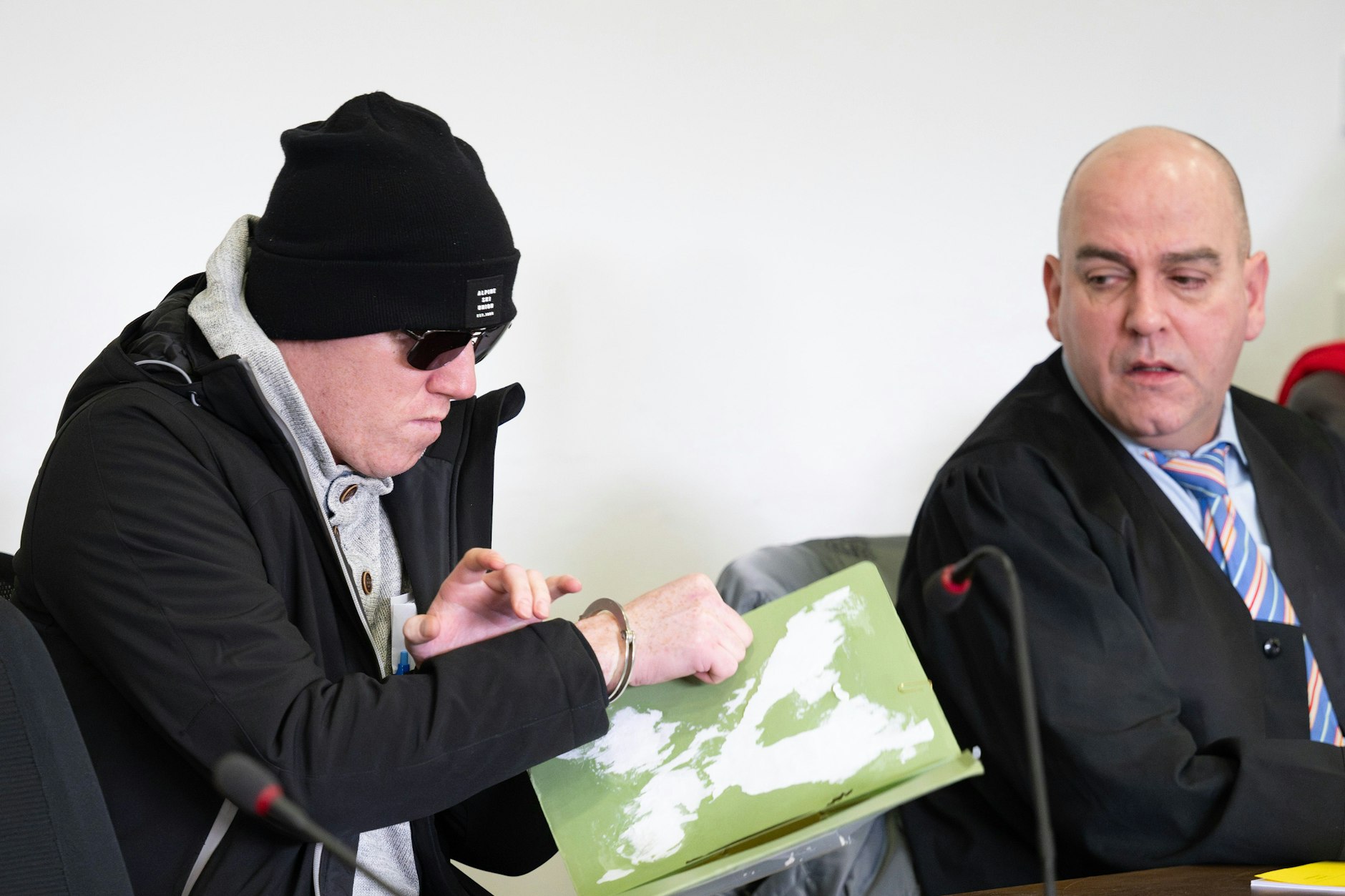 Einer der beiden Angeklagten (l) sitzt vor Beginn der Hauptverhandlung des Potsdamer Landgerichts neben seinem Anwalt.