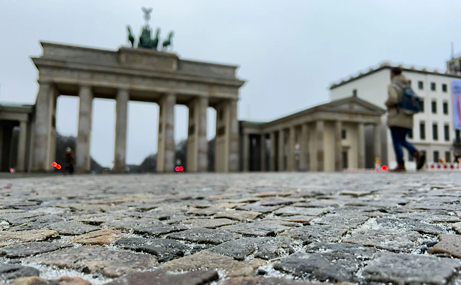 Eine dünne Eisschicht liegt über den Pflastersteinen vor dem Brandenburger Tor.  