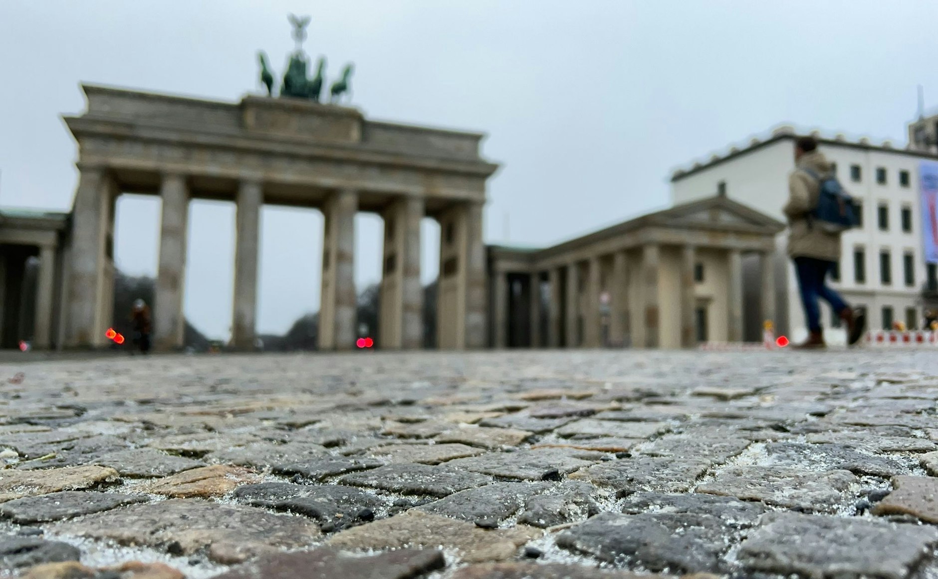 Eine dünne Eisschicht liegt über den Pflastersteinen vor dem Brandenburger Tor.