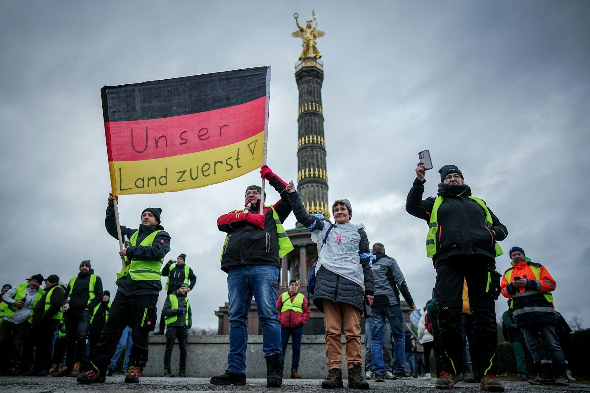 Teilnehmer der Großkundgebung protestieren mit einer Deutschlandfahne vor der Siegessäule.