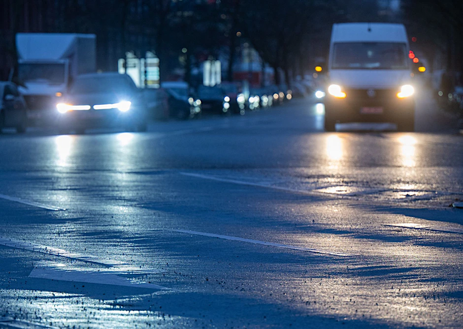 Autos fahren am Morgen über eine vereiste Straße im Bezirk Charlottenburg.  