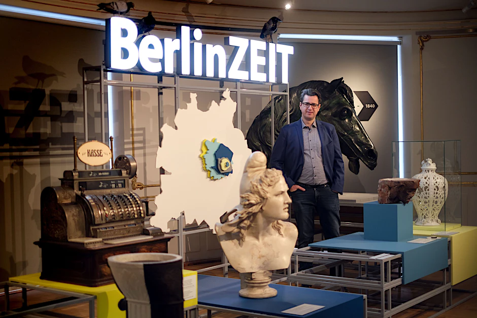 Kurator Gernot Schaulinski
            inmitten der Objekte, die den Rundgang durch die überarbeitete Ausstellung „BerlinZeit“ eröffnen. Der Pferdekopf hinter ihm ist das einzige verbliebene Originalteil der Quadriga vom Brandenburger Tor.