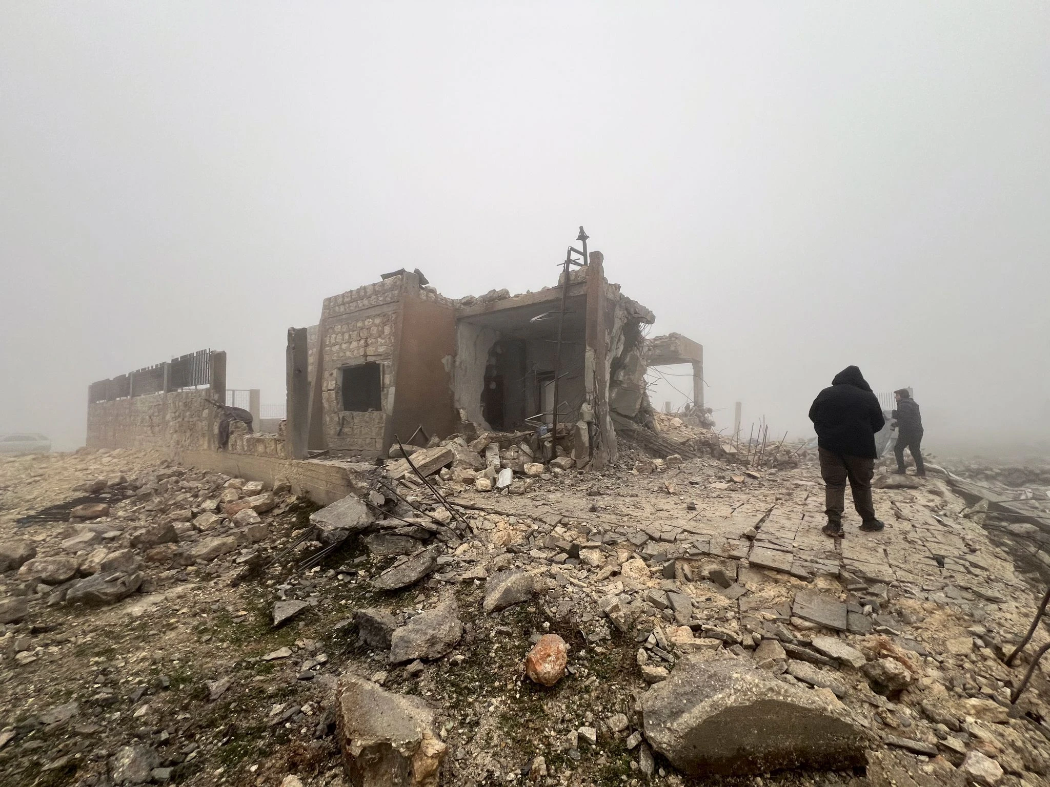 Syrer blicken auf eine verlassene medizinische Einrichtung, die nach Angaben der freiwilligen Rettungsorganisation White Helmets am späten Montagabend von iranischen Raketen getroffen wurde.  