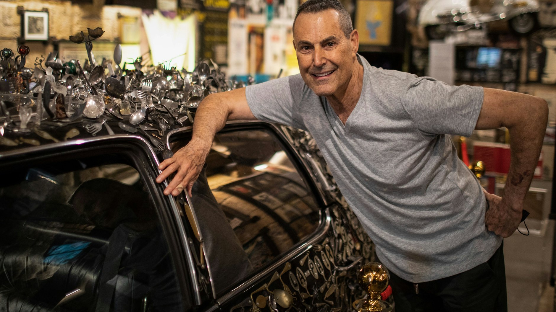 Uri Geller steht in seinem Museum neben einem Cadillac aus dem Jahr 1976, der mit selbstgebogenem Besteck bedeckt ist.