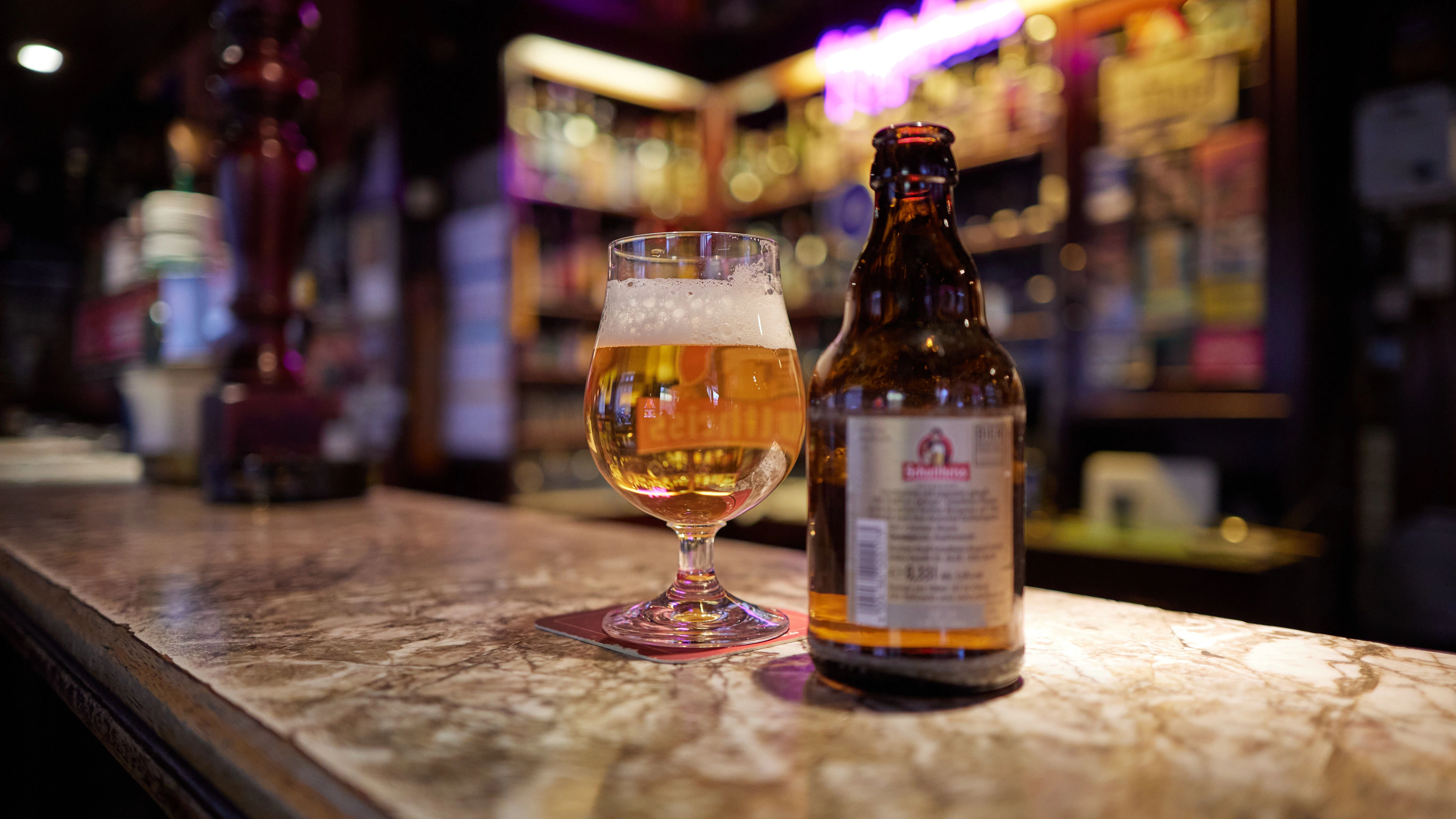 Eine Flasche Bier und ein Glas mit Bier stehen auf dem Tresen von der Kultkneipe Kupferkanne in der Steinmetzstraße in Schöneberg. An den holzvertäfelten Wänden hängen viele Poster und Bilder des Fußball-Zweitligisten Hertha BSC, dazu alte Mannschaftsfotos und Pokale.