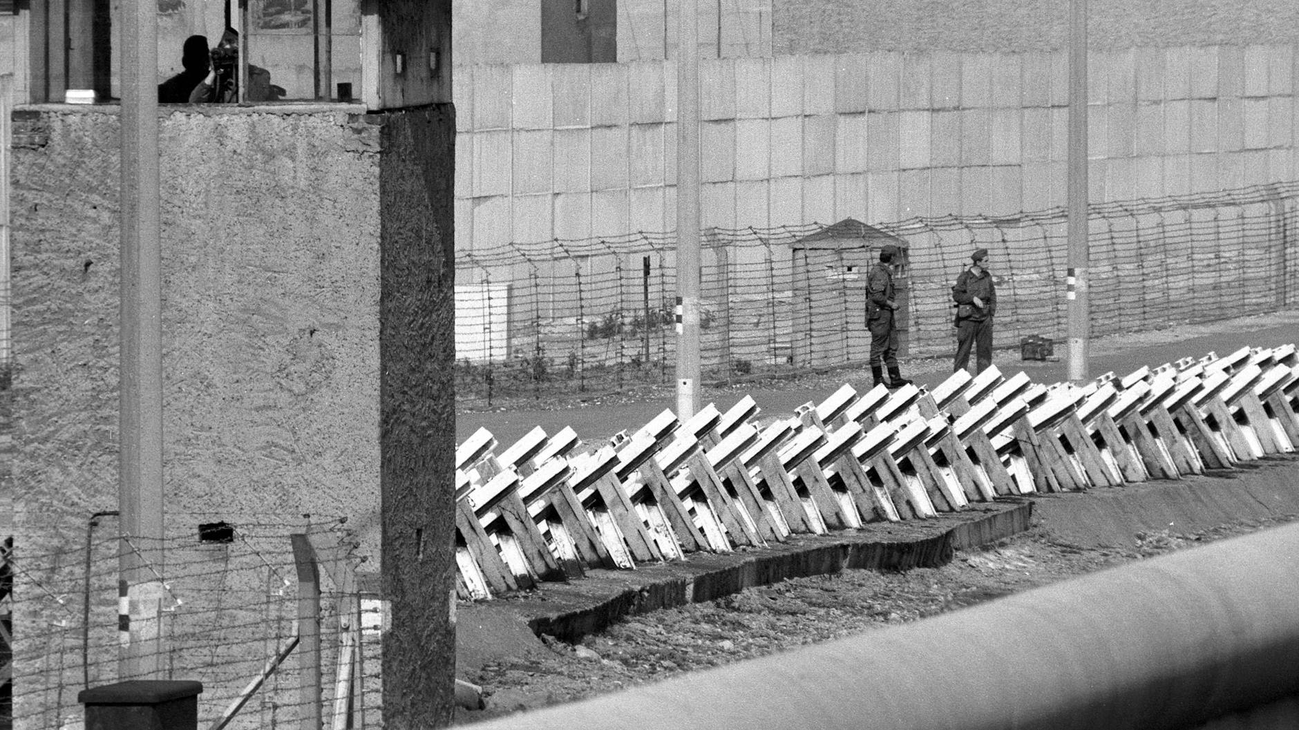 Blick auf den Todesstreifen an der Berliner Mauer, wo zwei Wachposten patrouillieren (1980). 