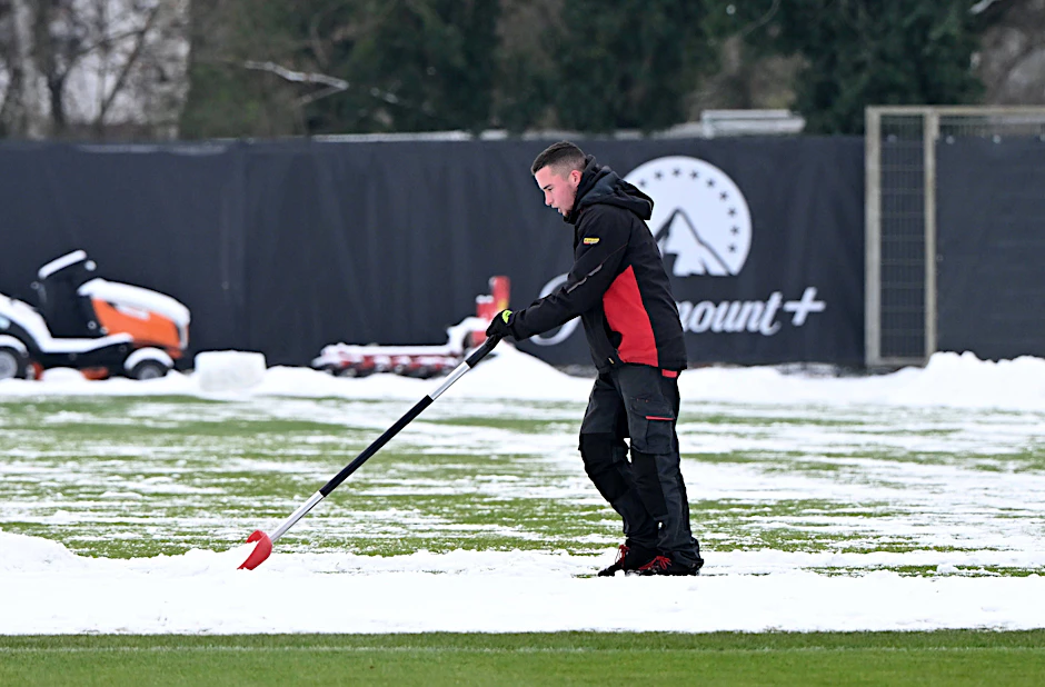 Ein Mitarbeiter beseitigt Schnee auf einem Trainingsplatz.