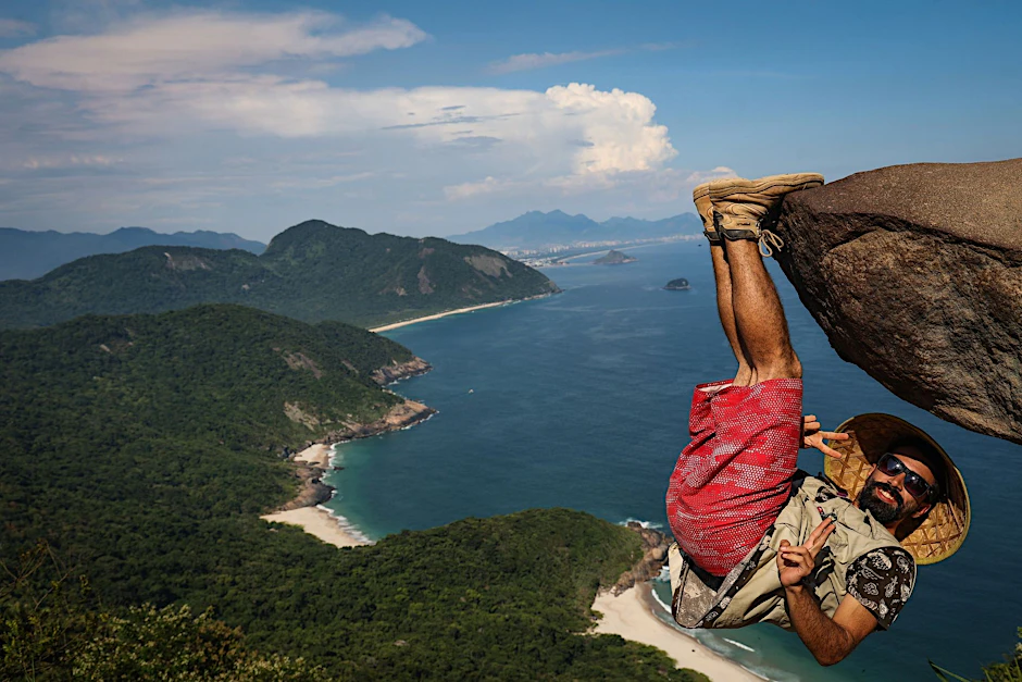 Frage des Blickwinkels: Ein Mann hängt für ein Foto am Felsen Pedra do Telégrafo bei Rio de Janeiro.