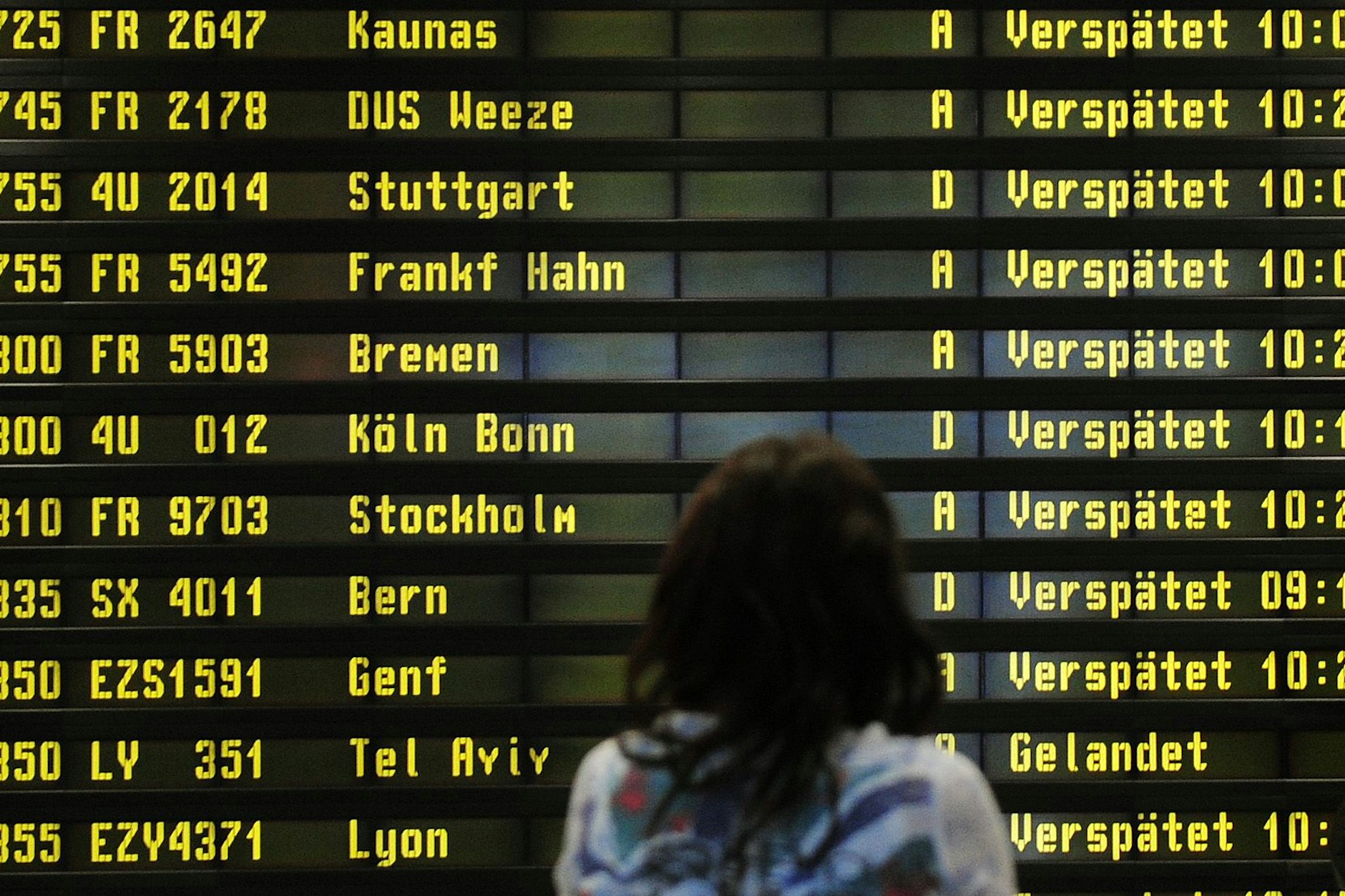 Eine Frau steht auf dem Flughafen Berlin-Schönefeld vor einer Anzeigetafel, auf der verspätete Flüge aufgelistet werden.&nbsp;