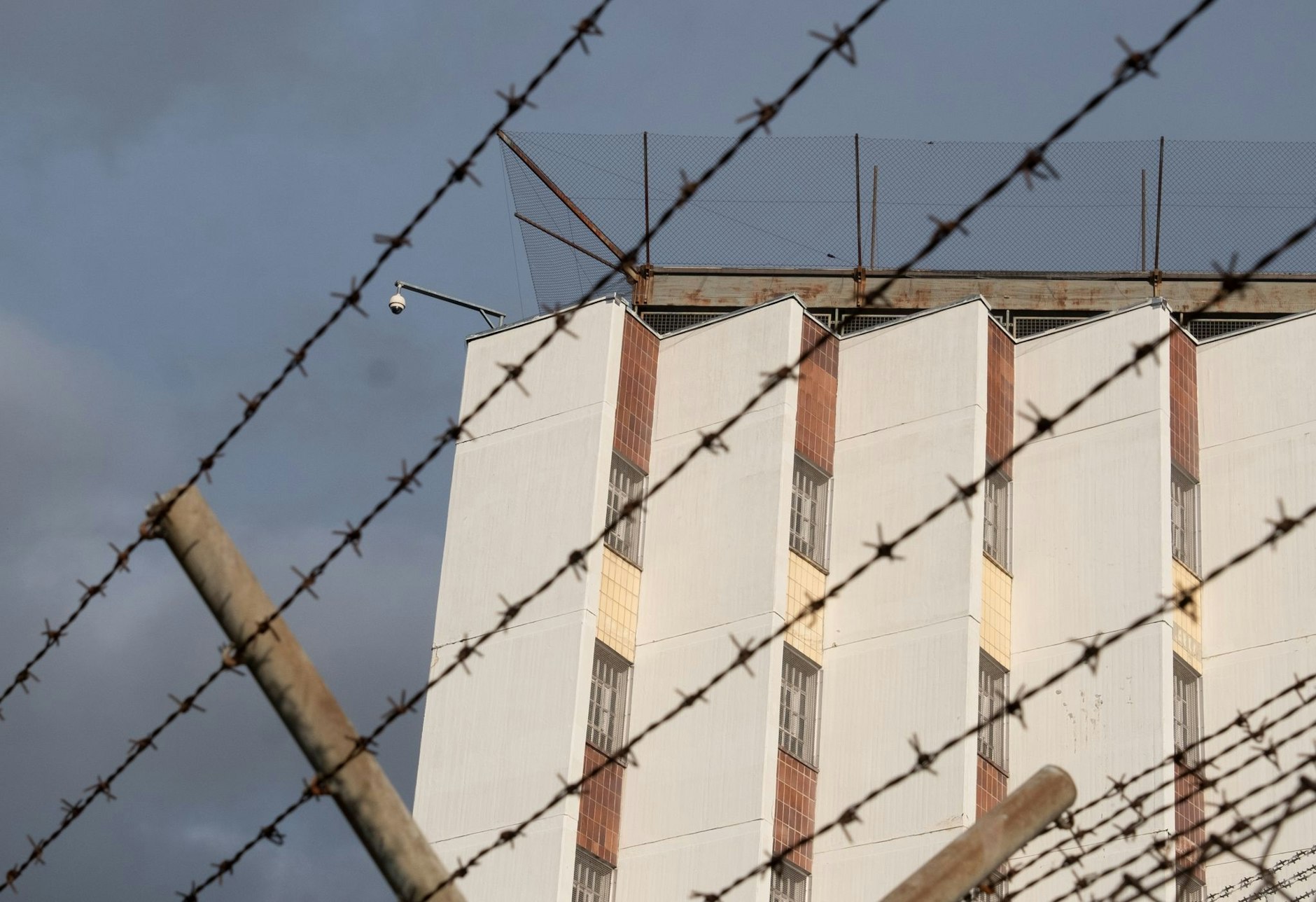 Ein Stacheldrahtzaun umzäunt das Gelände einer Justizvollzugsanstalt.  