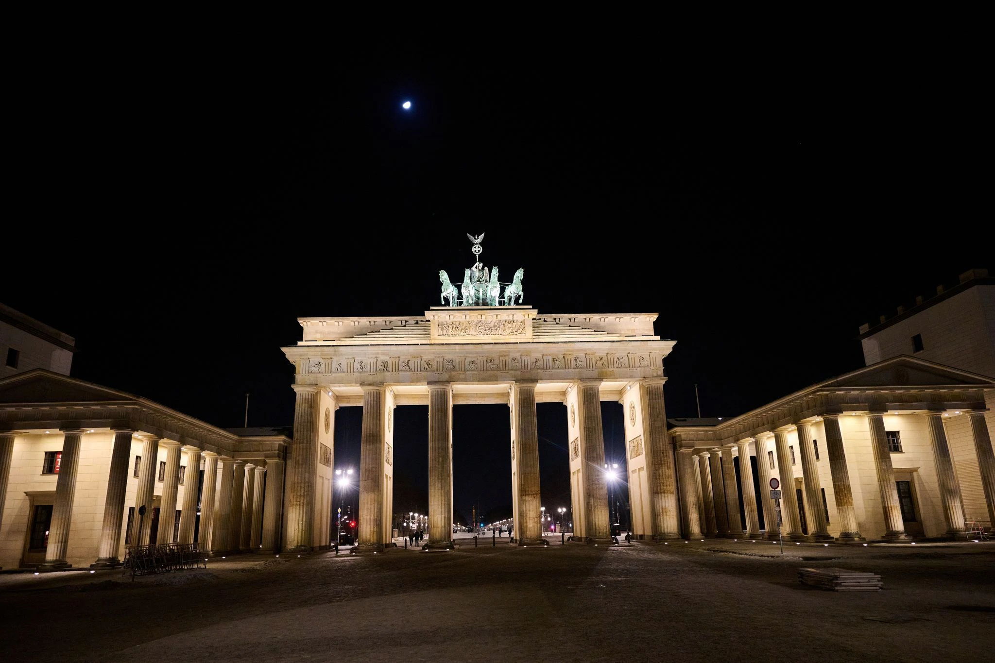 Postkarten-Motiv: Das Brandenburger Tor, Wahrzeichen von Berlin, wird in der Dunkelheit angeleuchtet.  