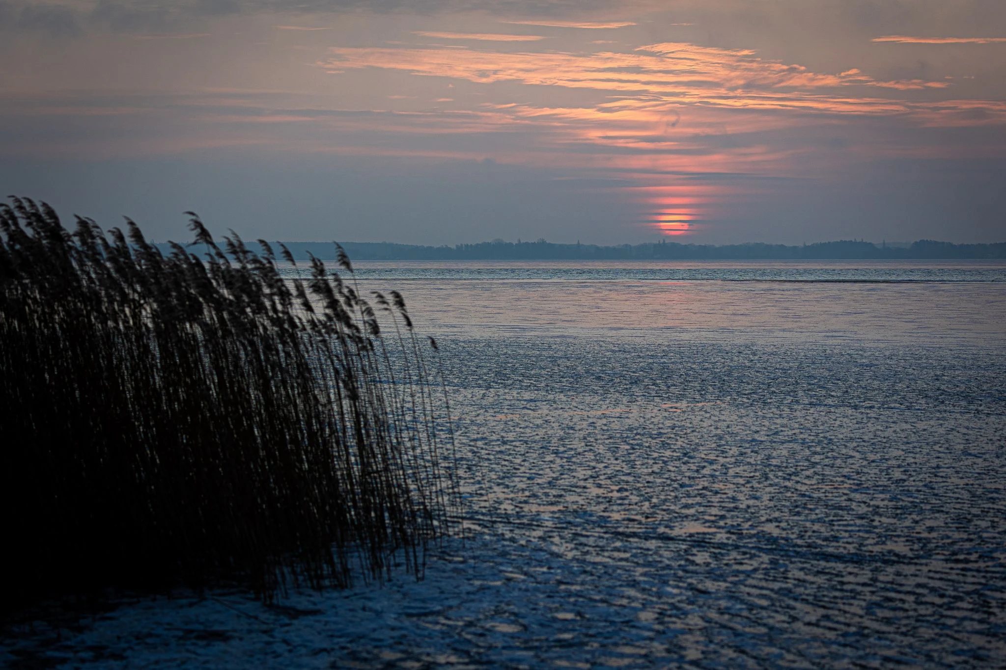Die Sonne geht über dem teilweise zugefrorenen Steinhuder Meer in Niedersachsen auf.  